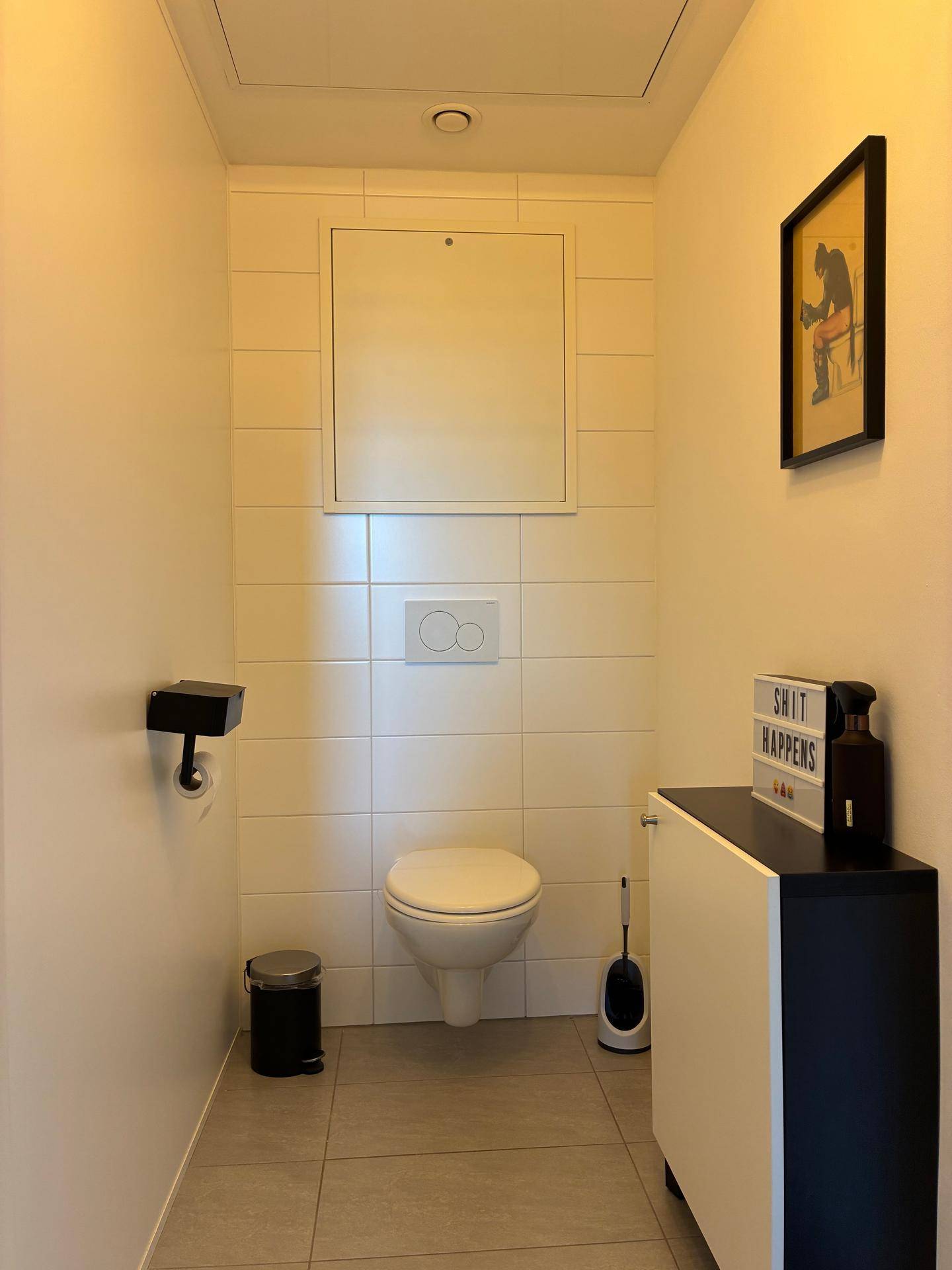 Separates WC mit Wand-WC und Fliesen an den Wänden, minimalistisch eingerichtet.