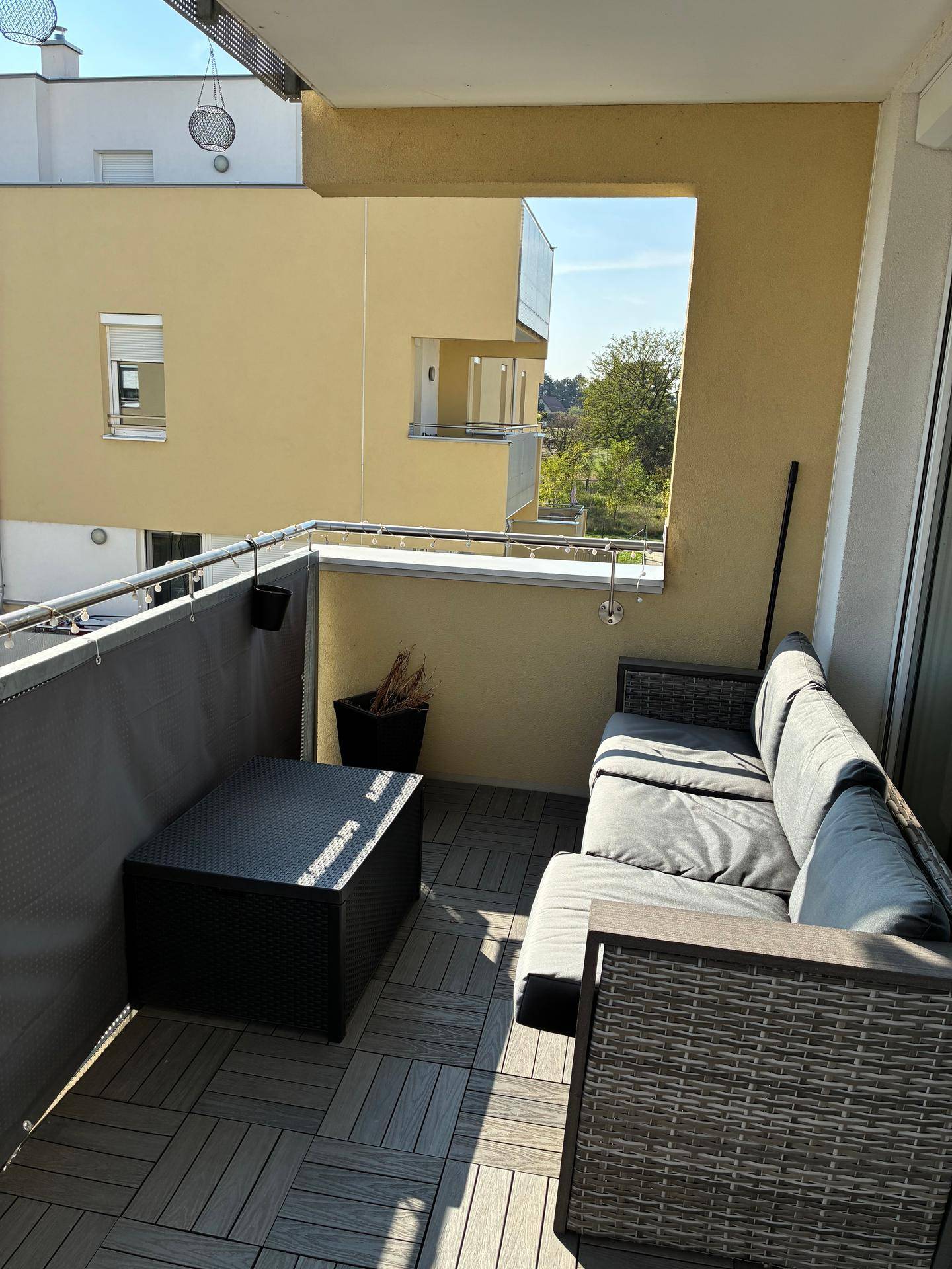 Heller Balkon mit bequemen Outdoor-Möbeln und Blick auf die Umgebung.