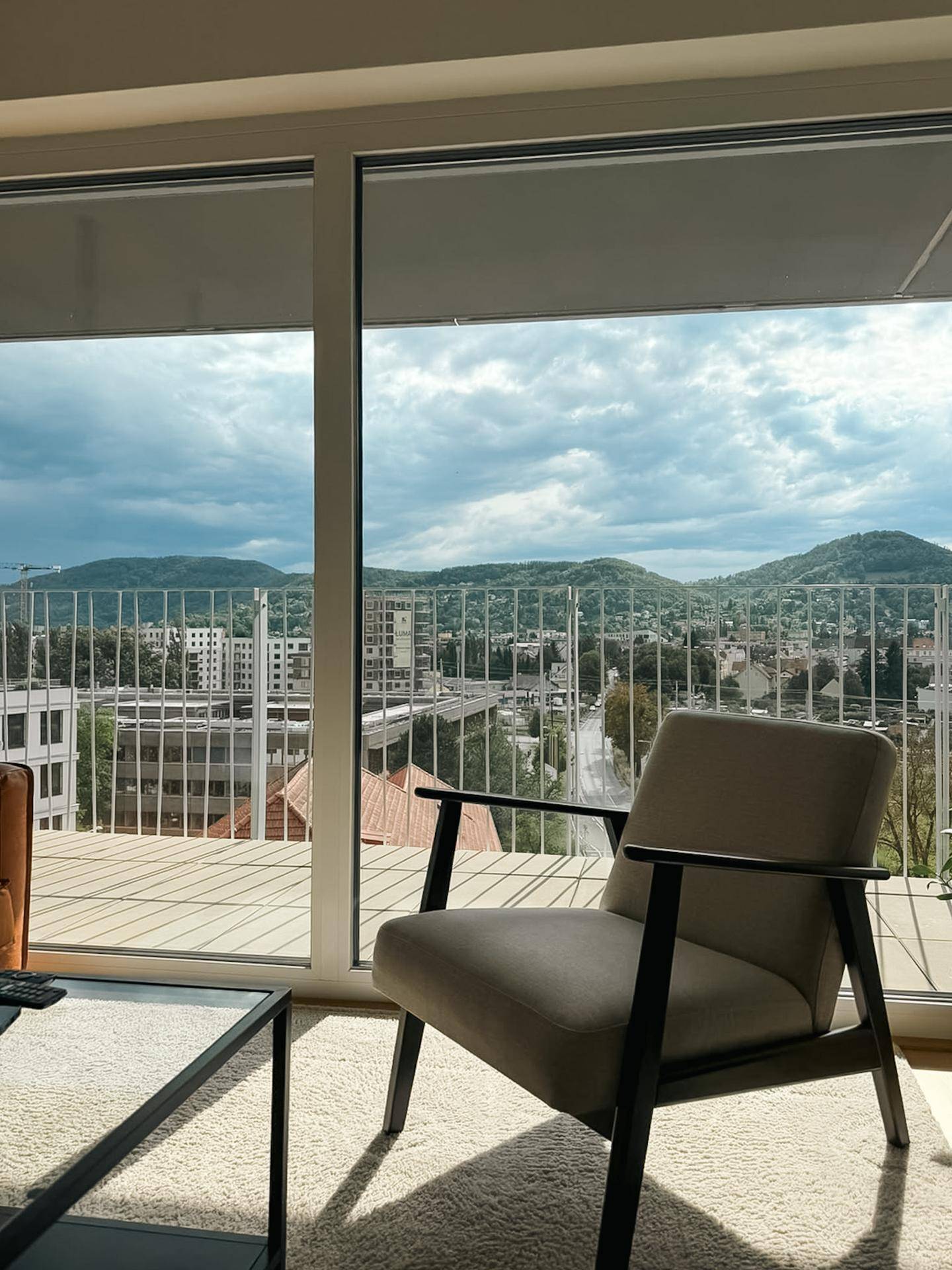 Weitblick auf die umliegende Landschaft und Berge von einem hellen Wohnzimmer aus.