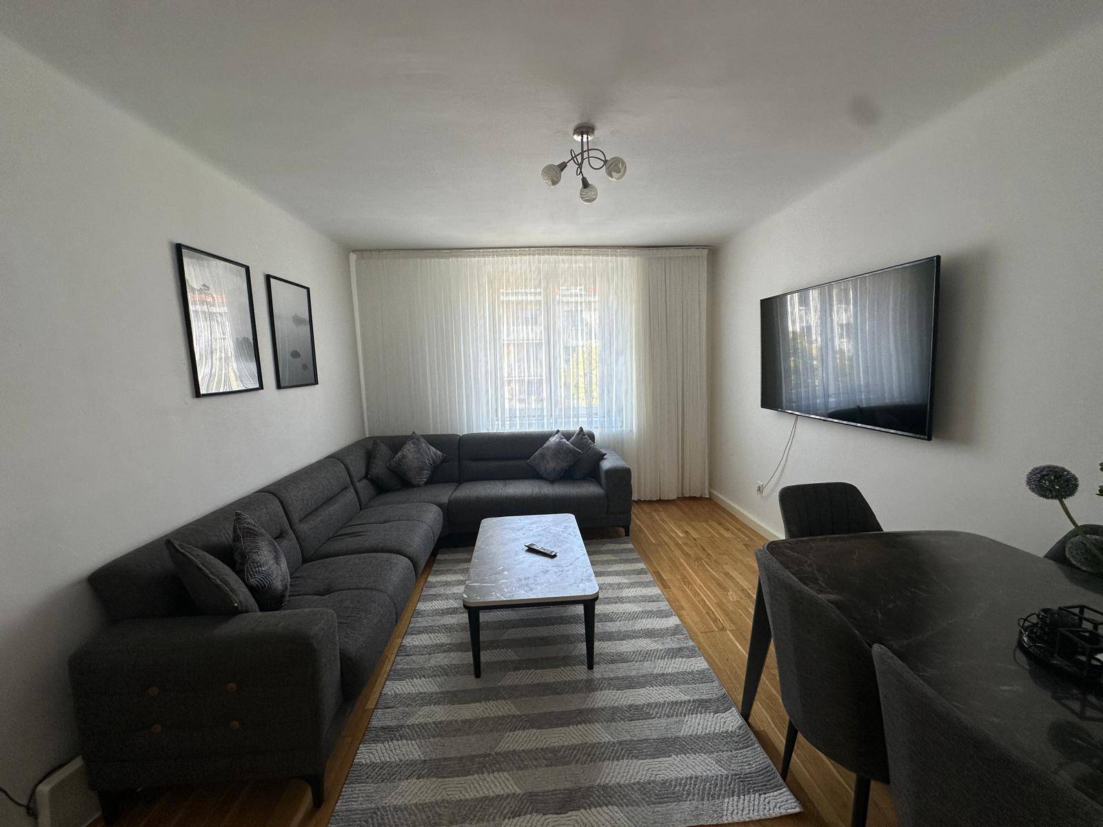 Heller Wohn- und Essbereich mit Ecksofa, Esstisch und Holzboden.