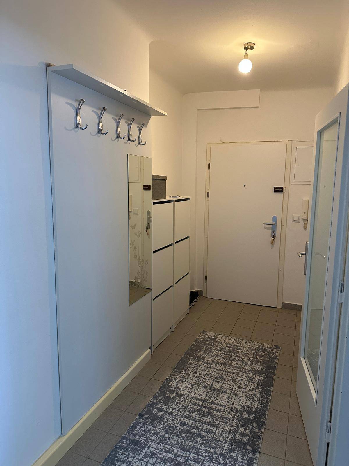 Eingangsbereich mit Garderobe, Schuhschrank und Fliesenboden, helle Wände.