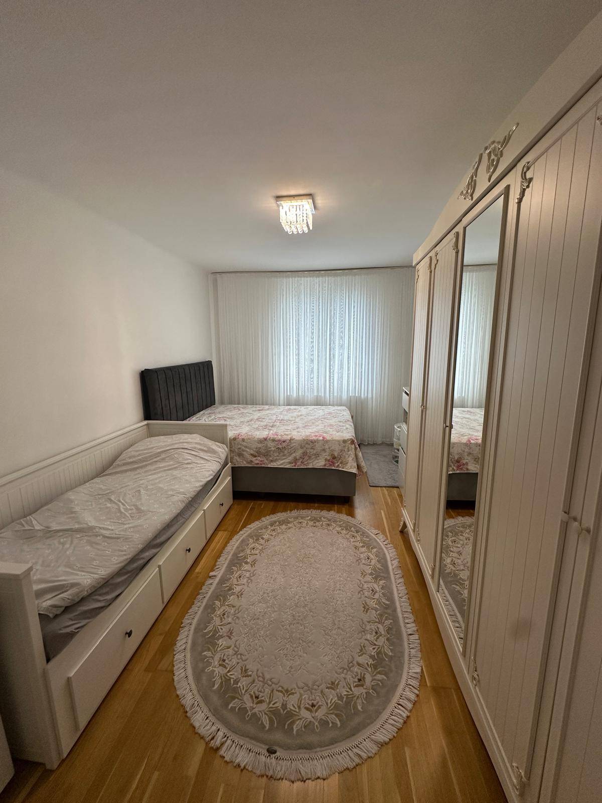 Schlafzimmer mit zwei Betten, weißem Kleiderschrank und Holzboden.