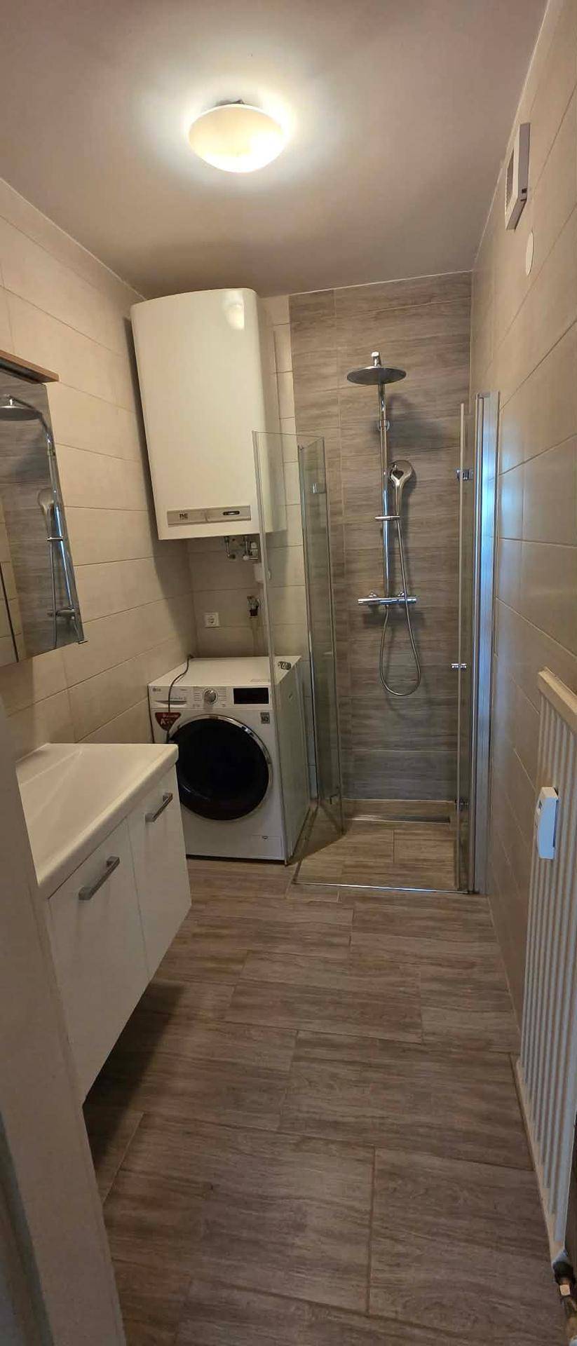 Modernes Badezimmer mit Duschkabine, Waschbeckenunterschrank und Waschmaschine.