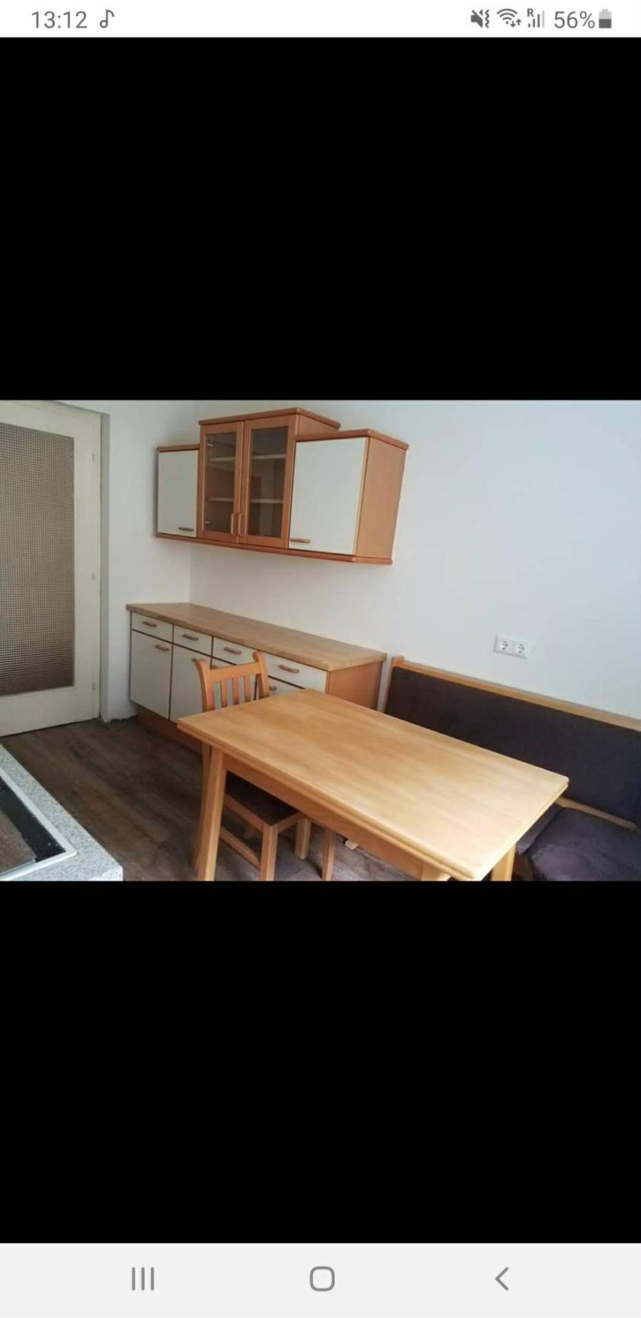 Essbereich in der Küche mit Holztisch, Sitzbank und weiteren Küchenschränken.
