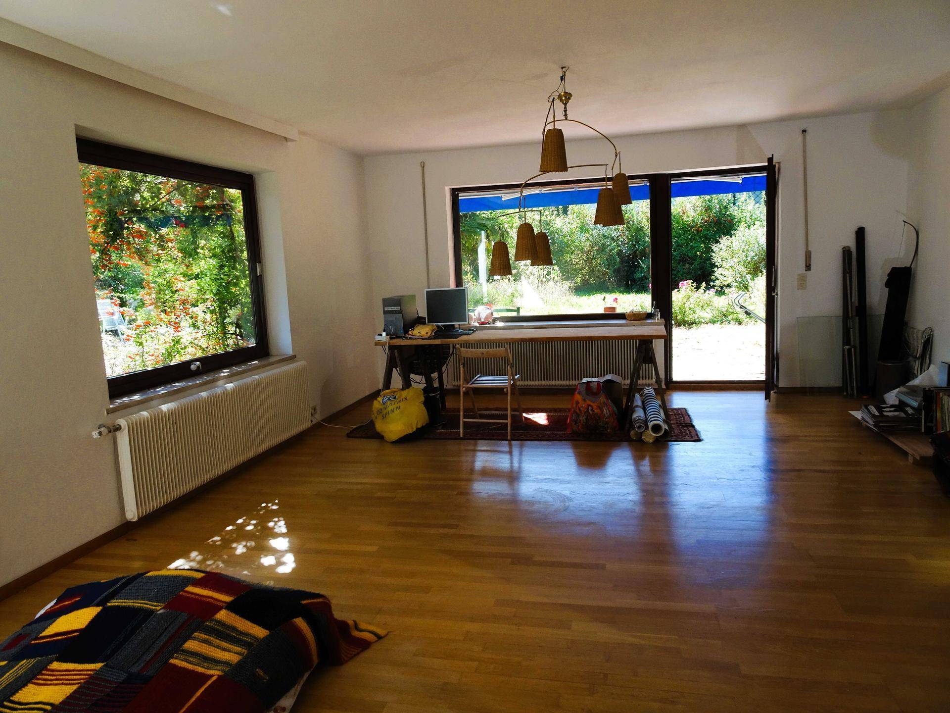 Helles Wohnzimmer mit Holzboden, großen Fenstern und Zugang zum Gartenbereich.