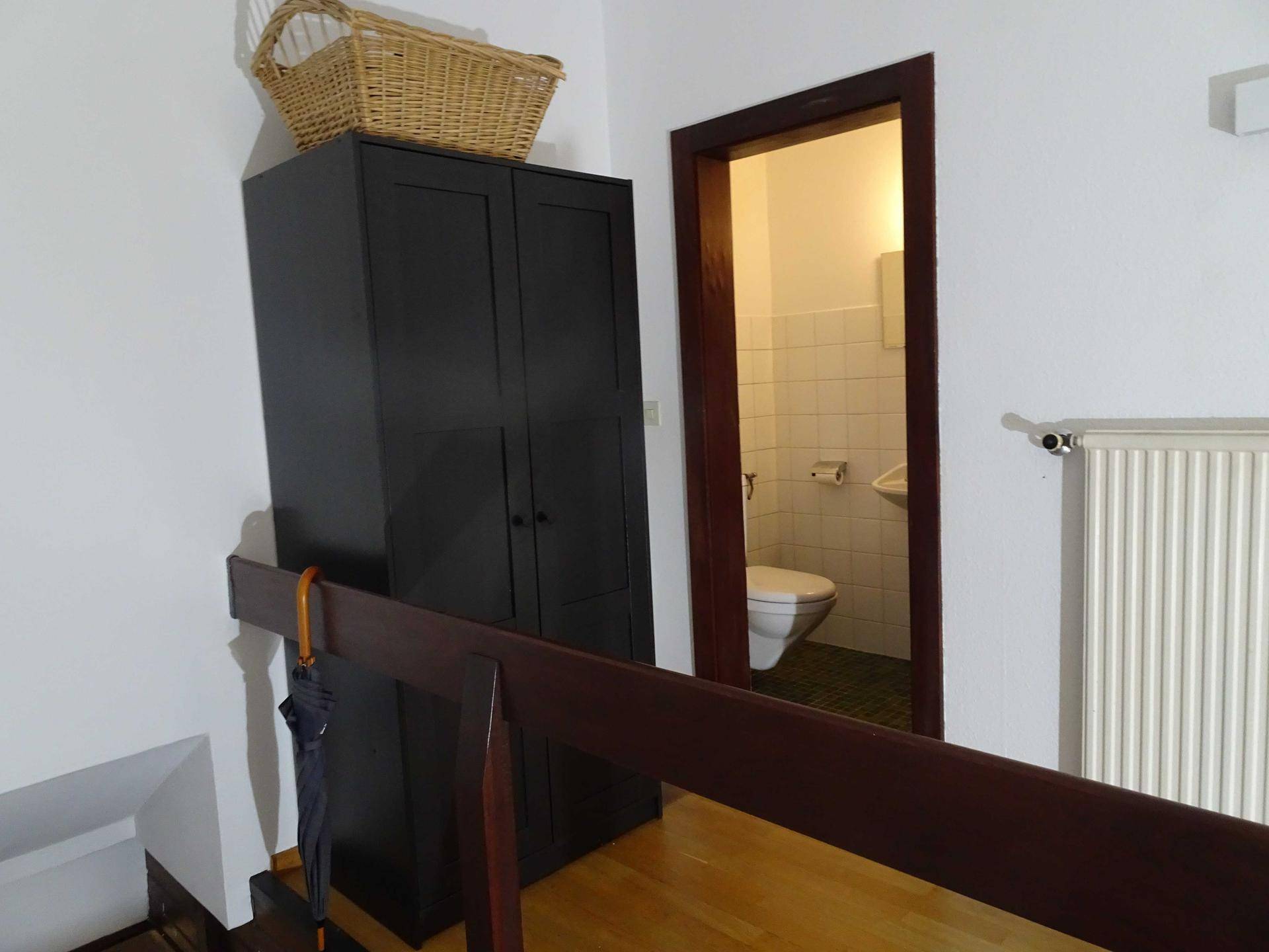 Detailansicht des Flurs mit Schrank und offenem Zugang zu einem gefliesten Gäste-WC.