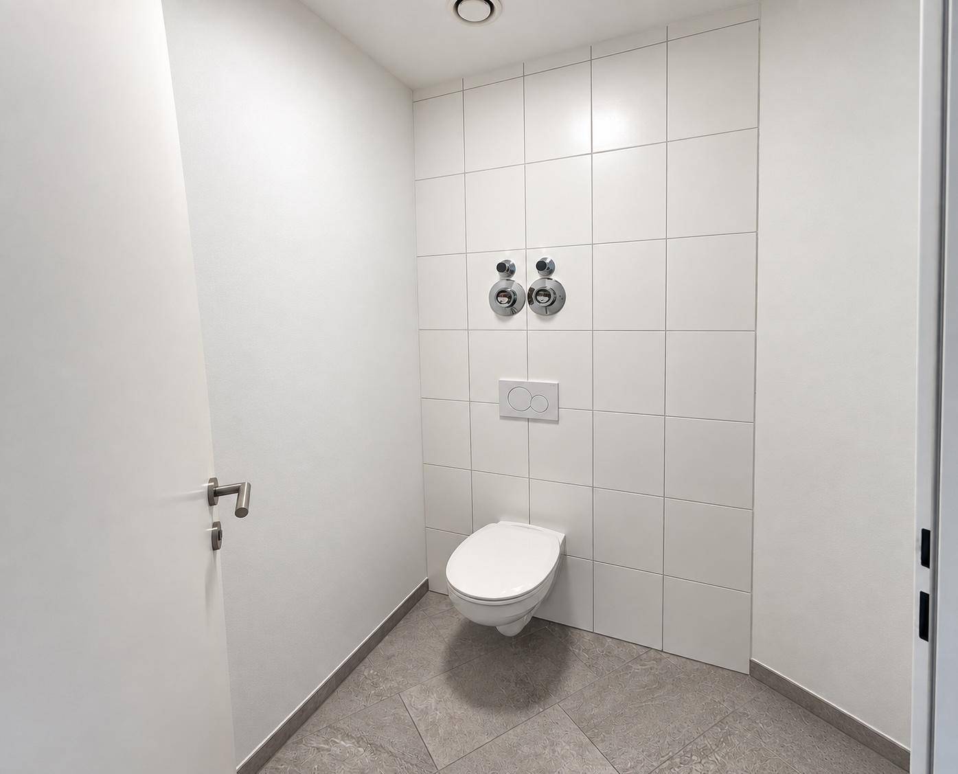 Separates WC mit Wand-WC und modernen Fliesen, in einem minimalistischen Design gehalten.
