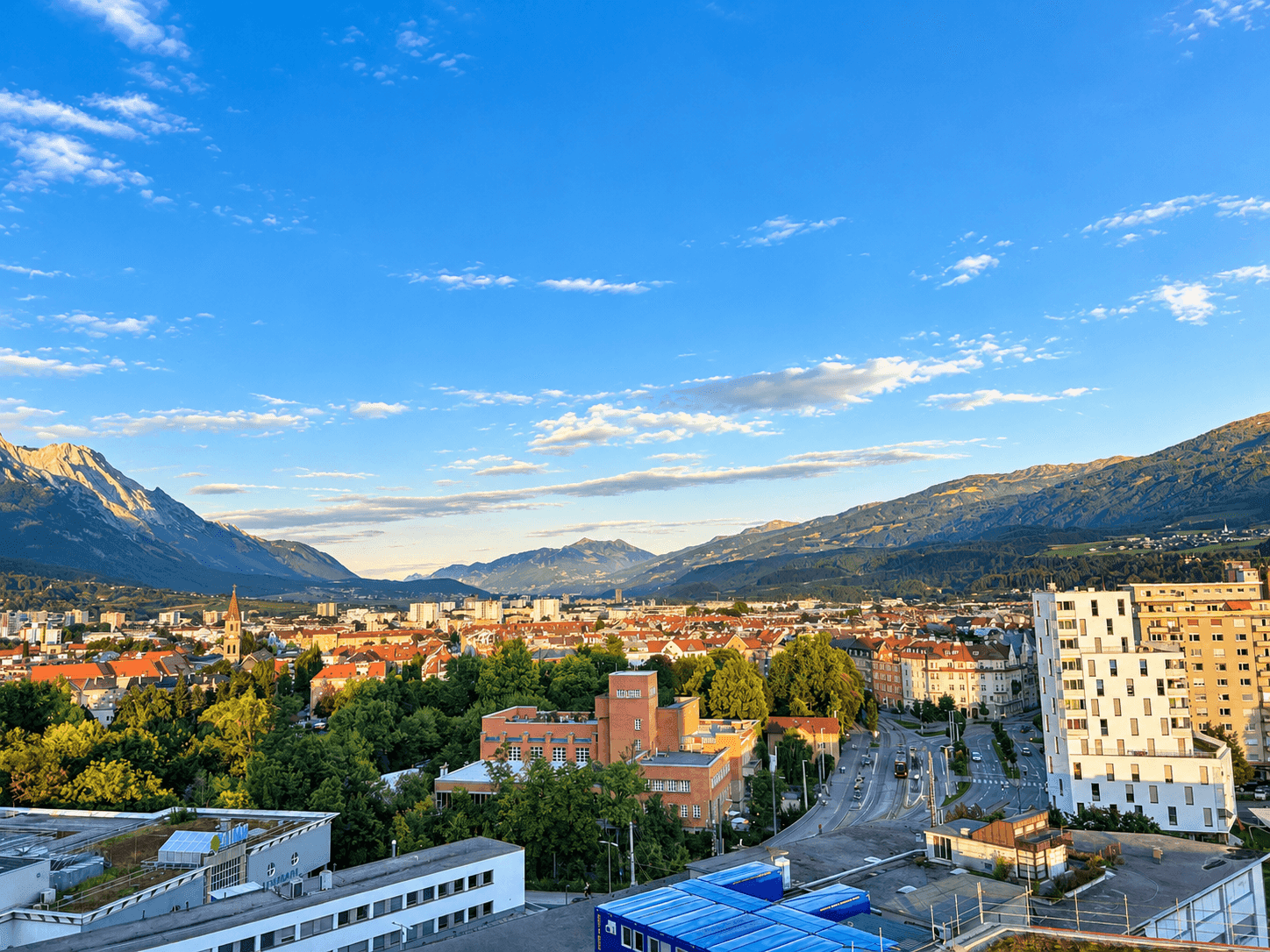 Panoramablick auf die Stadt und die umliegenden Berge an einem sonnigen Tag.