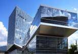 Moderne Architektur eines Gebäudes mit reflektierender Glasfassade unter blauem Himmel.
