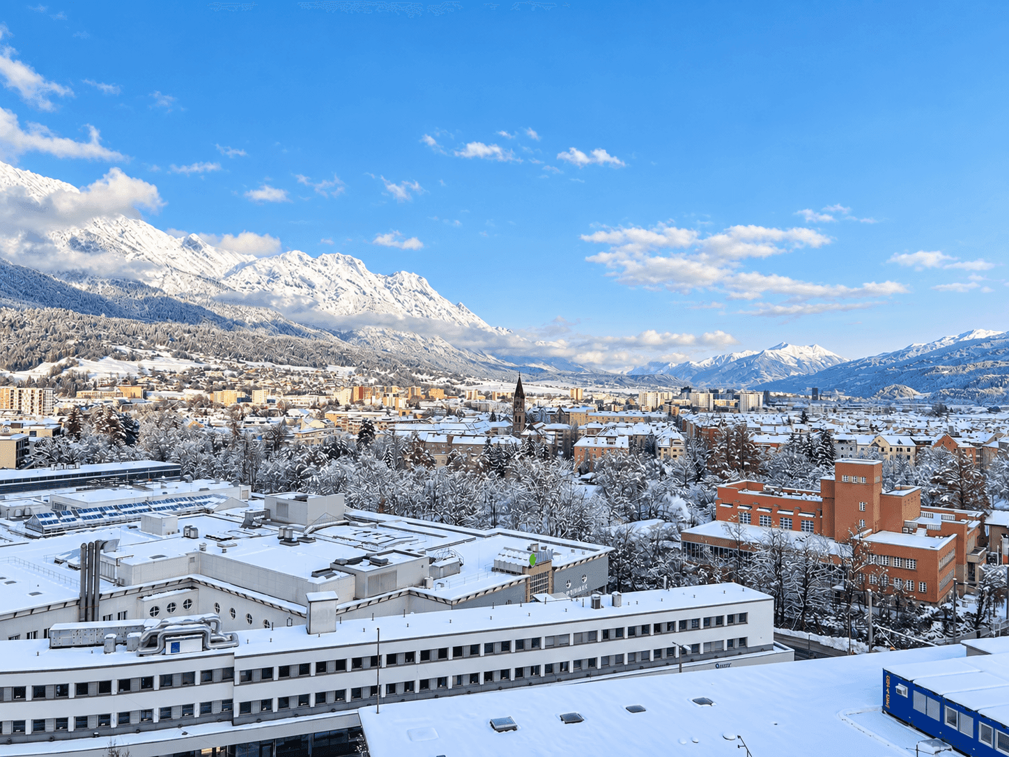 Winterlicher Panoramablick auf die verschneite Stadt und die majestätischen Berge.