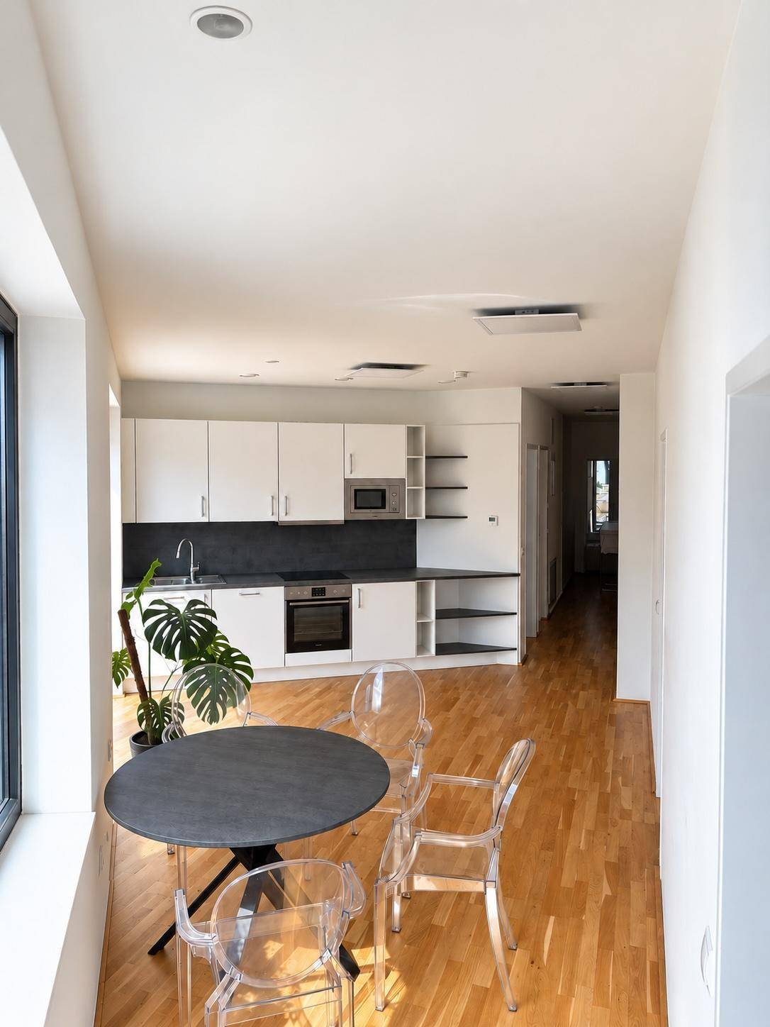 Moderne Einbauküche mit weißen Schränken, integrierten Geräten und Essbereich.