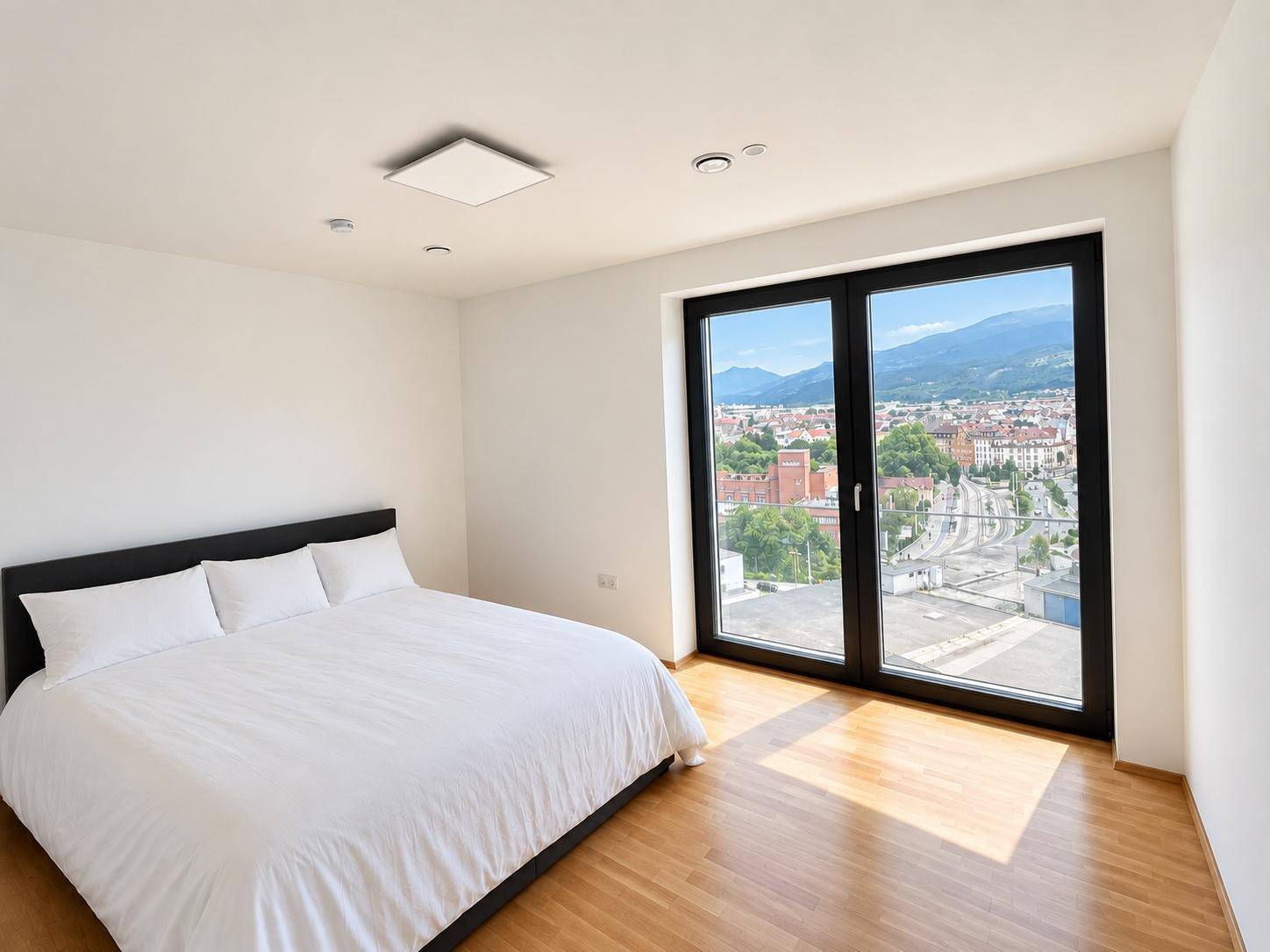 Modernes Schlafzimmer mit Holzboden, großem Fenster und weitem Blick auf die Stadt und Berge.
