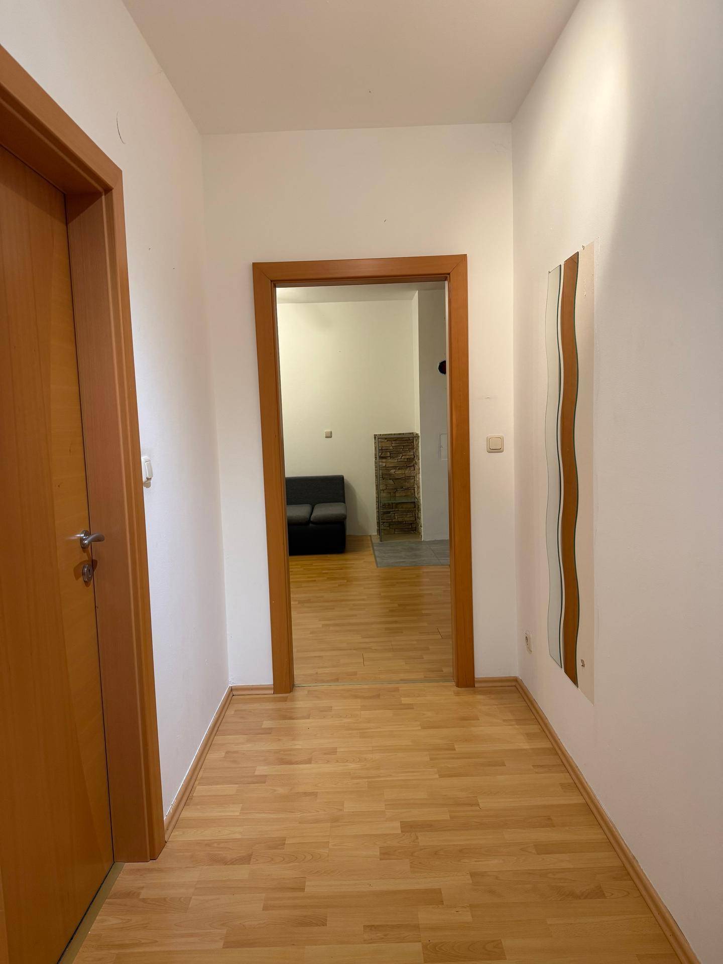 Heller Flur mit Holztüren und Laminatboden, der zu weiteren Räumen führt.