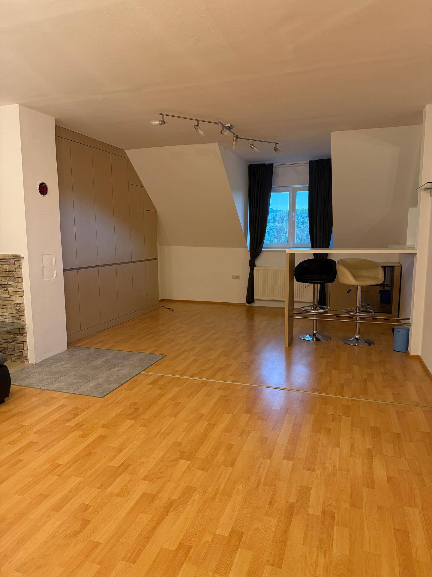 Geräumiges Wohnzimmer im Dachgeschoss mit Laminatboden, Einbauschränken und einer Bar.