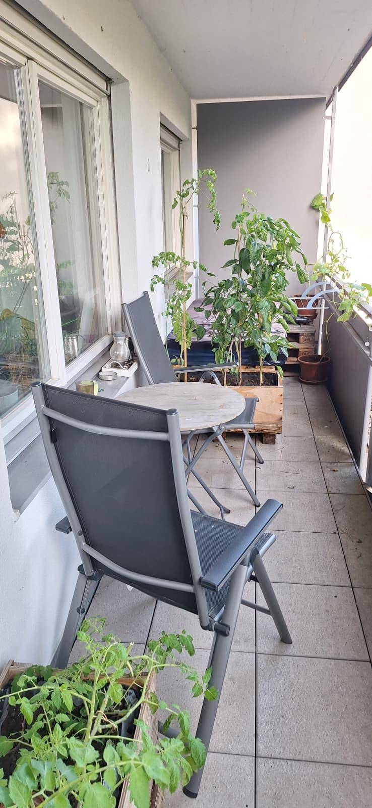 Gemütlicher Balkon mit Fliesenboden, Sitzgelegenheiten und vielen Pflanzen für eine grüne Atmosphäre.