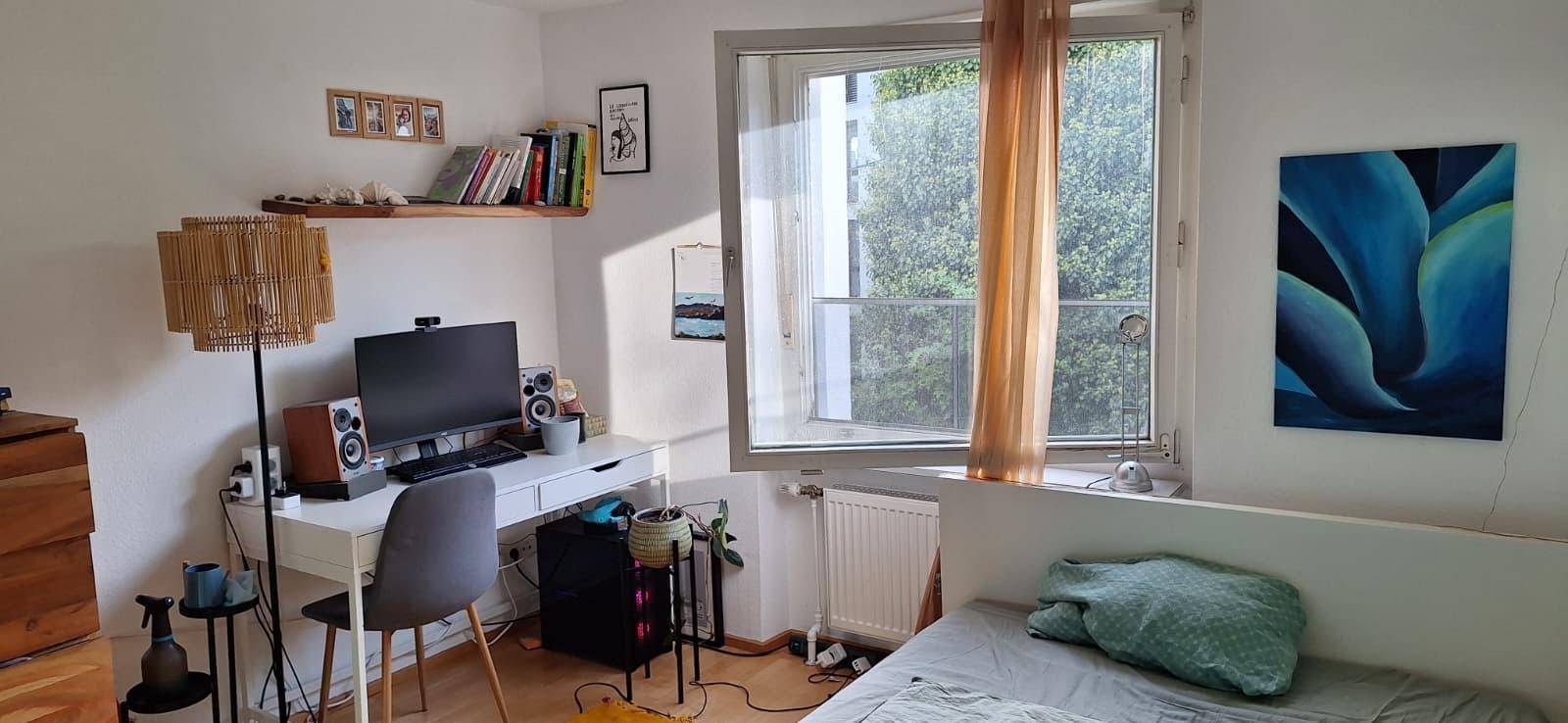 Helles Schlafzimmer mit Arbeitsbereich, Einzelbett und Fenster mit Blick auf die umliegende Natur.