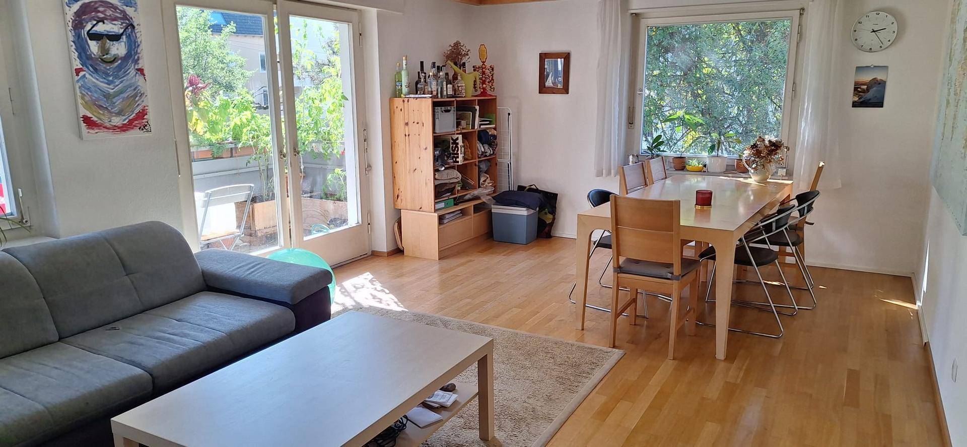 Heller Wohn- und Essbereich mit Holzfußboden, großem Esstisch und Zugang zum Außenbereich.