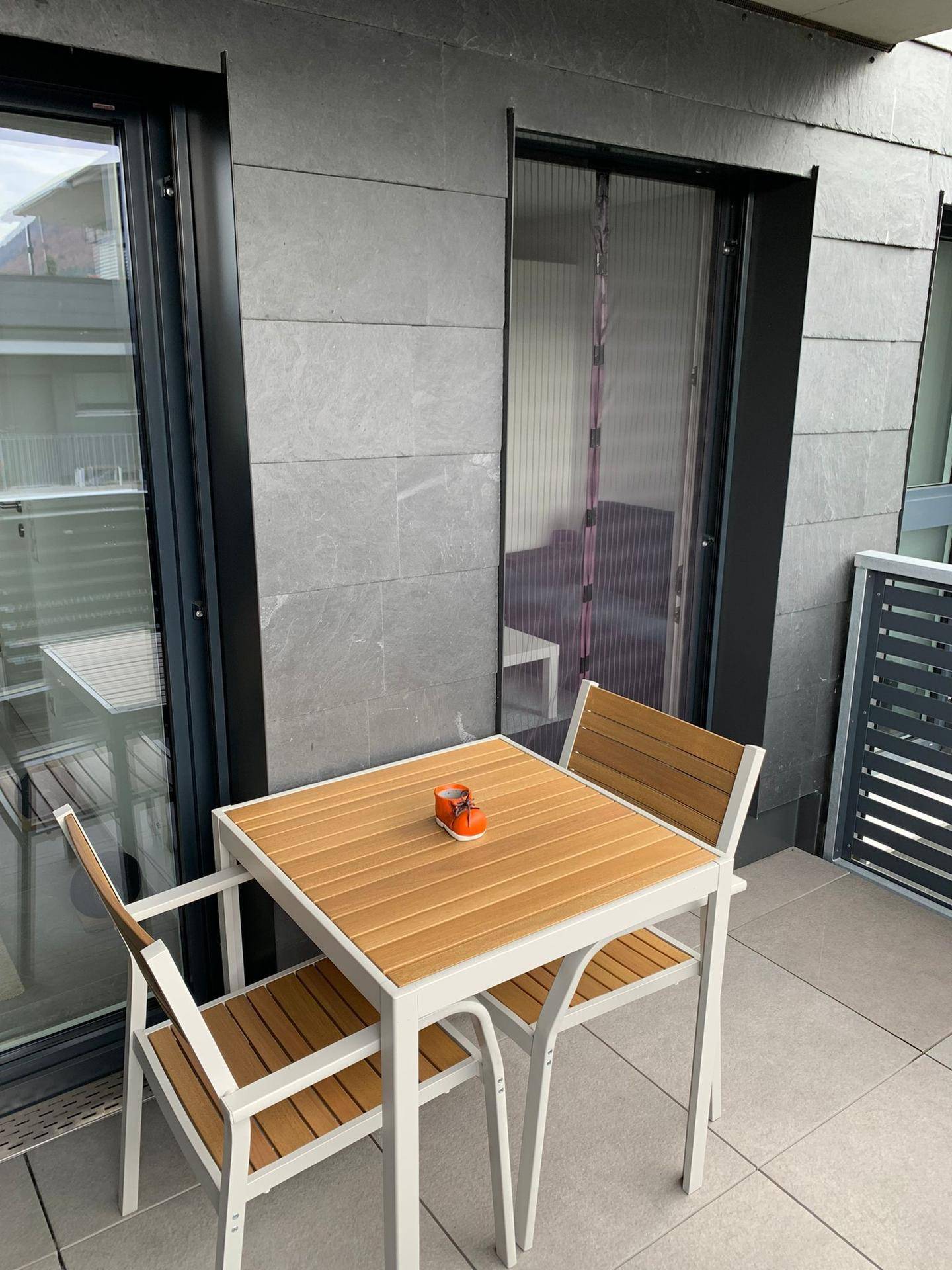 Gemütlicher Balkon mit Holztisch und Stühlen, ideal für entspannte Stunden im Freien.