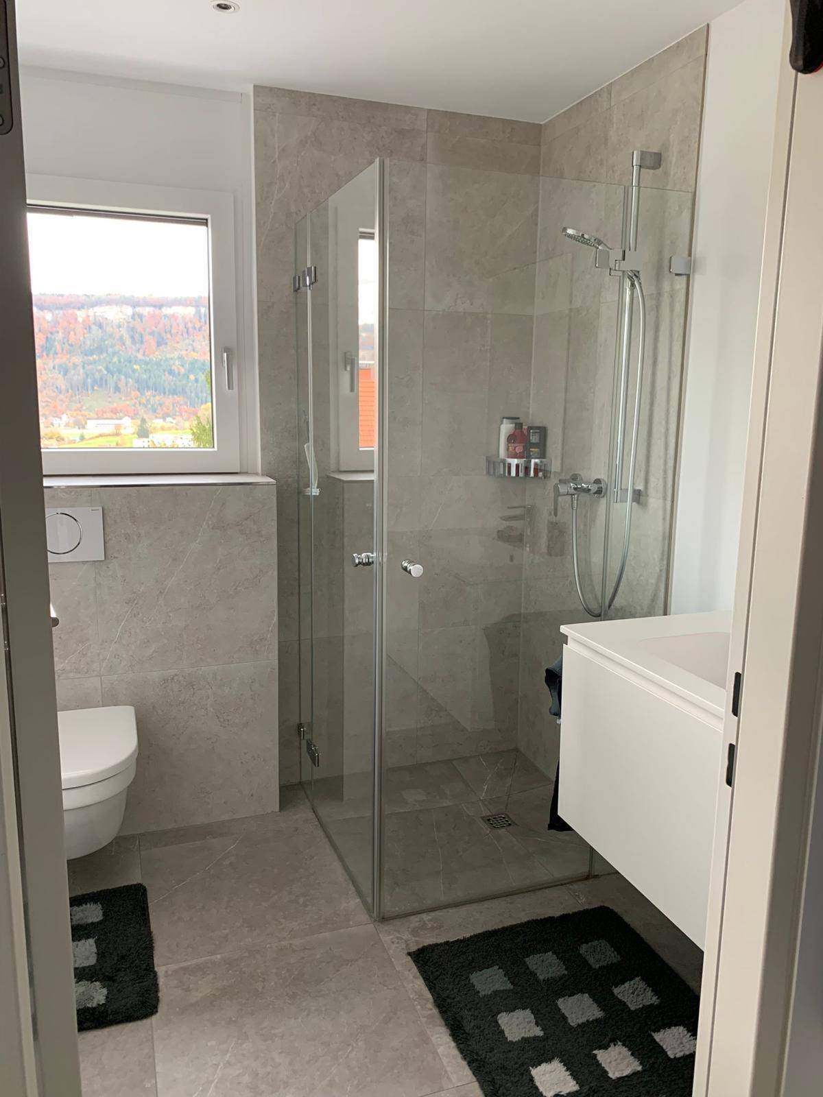 Modernes Badezimmer mit begehbarer Dusche, Wand-WC und Fenster für Tageslicht.
