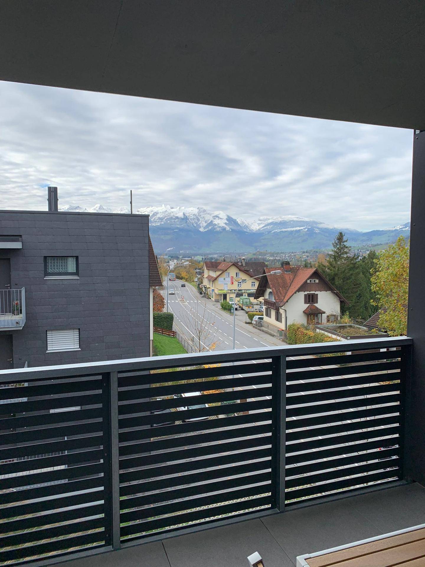 Balkon mit weitem Blick über die Straße auf eine malerische Berglandschaft.
