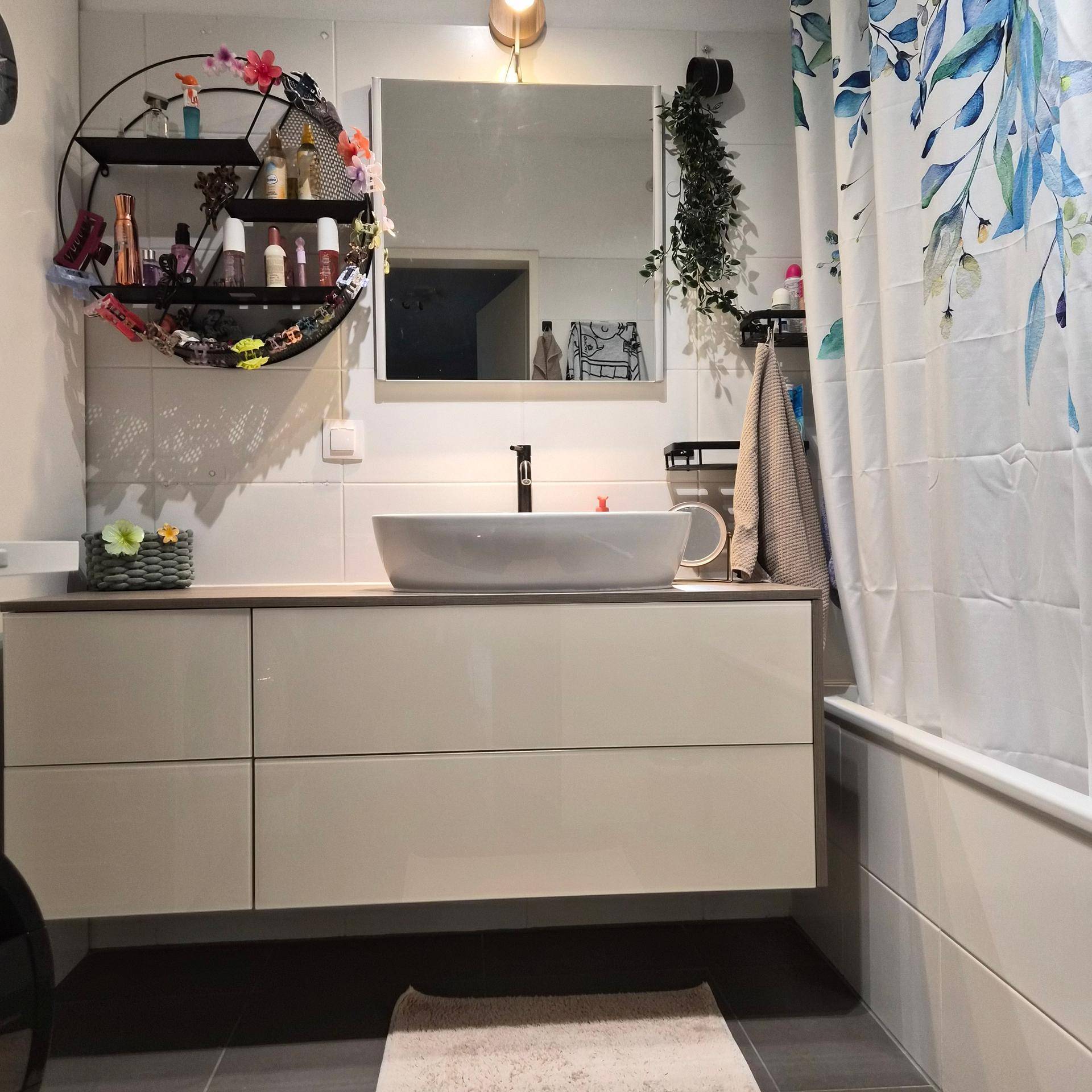 Modernes Badezimmer mit schwebendem Waschtisch, Einzelwaschbecken und floralem Duschvorhang.