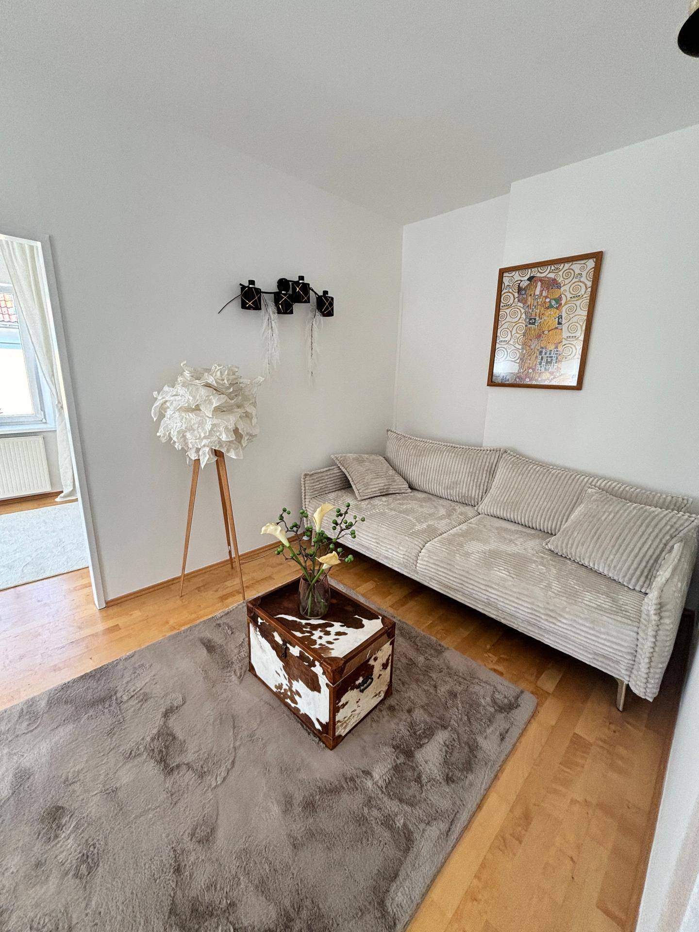 Gemütliches Wohnzimmer mit hellem Sofa, Teppich und dekorativem Couchtisch.