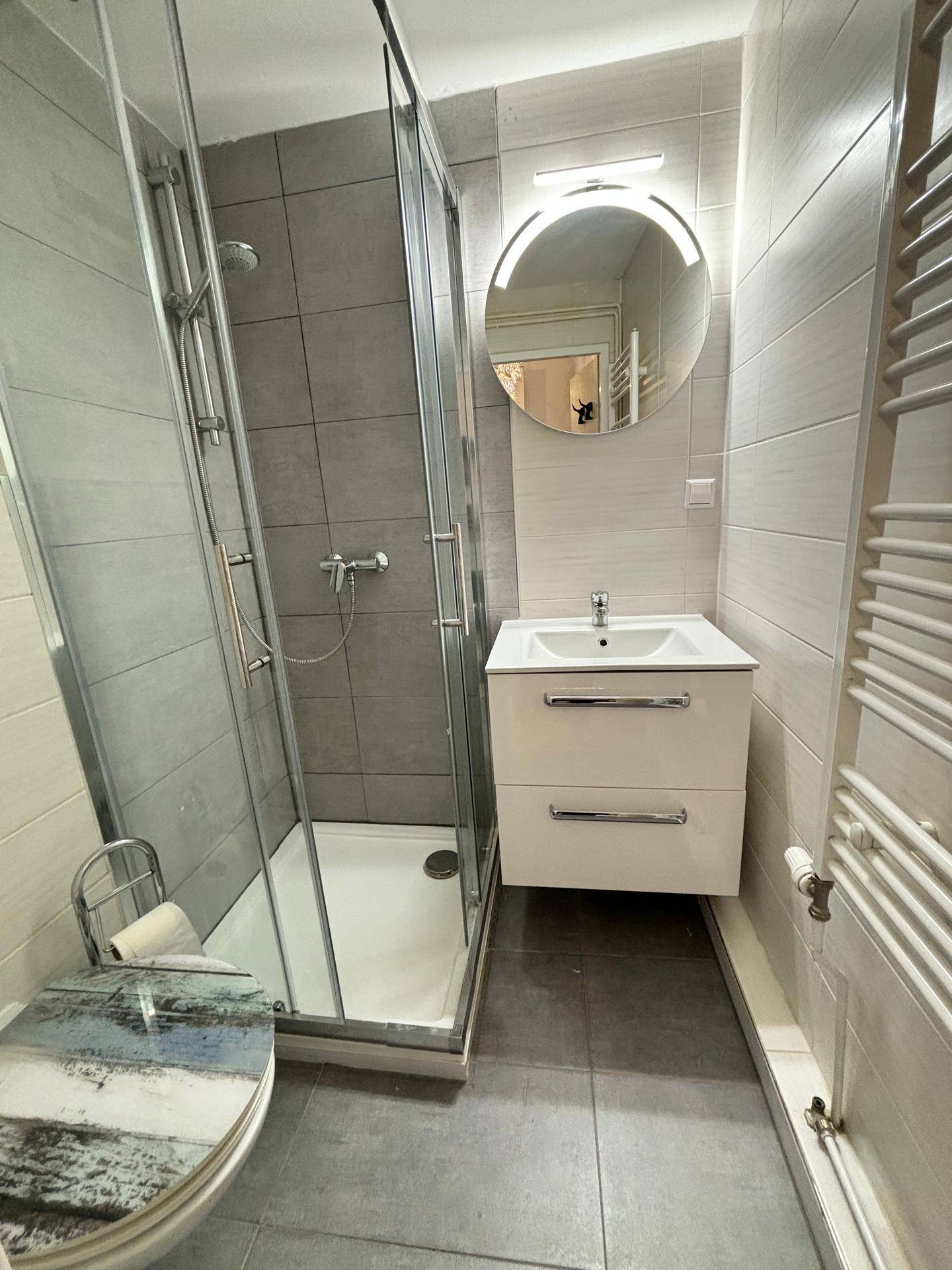 Modernes Badezimmer mit Duschkabine, Wandwaschbecken und beheiztem Handtuchhalter.