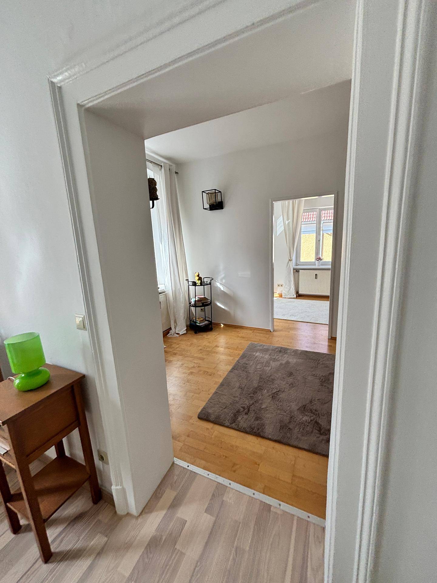 Heller Wohnbereich mit Holzfußboden und Zugang zu weiteren Räumen der Wohnung.