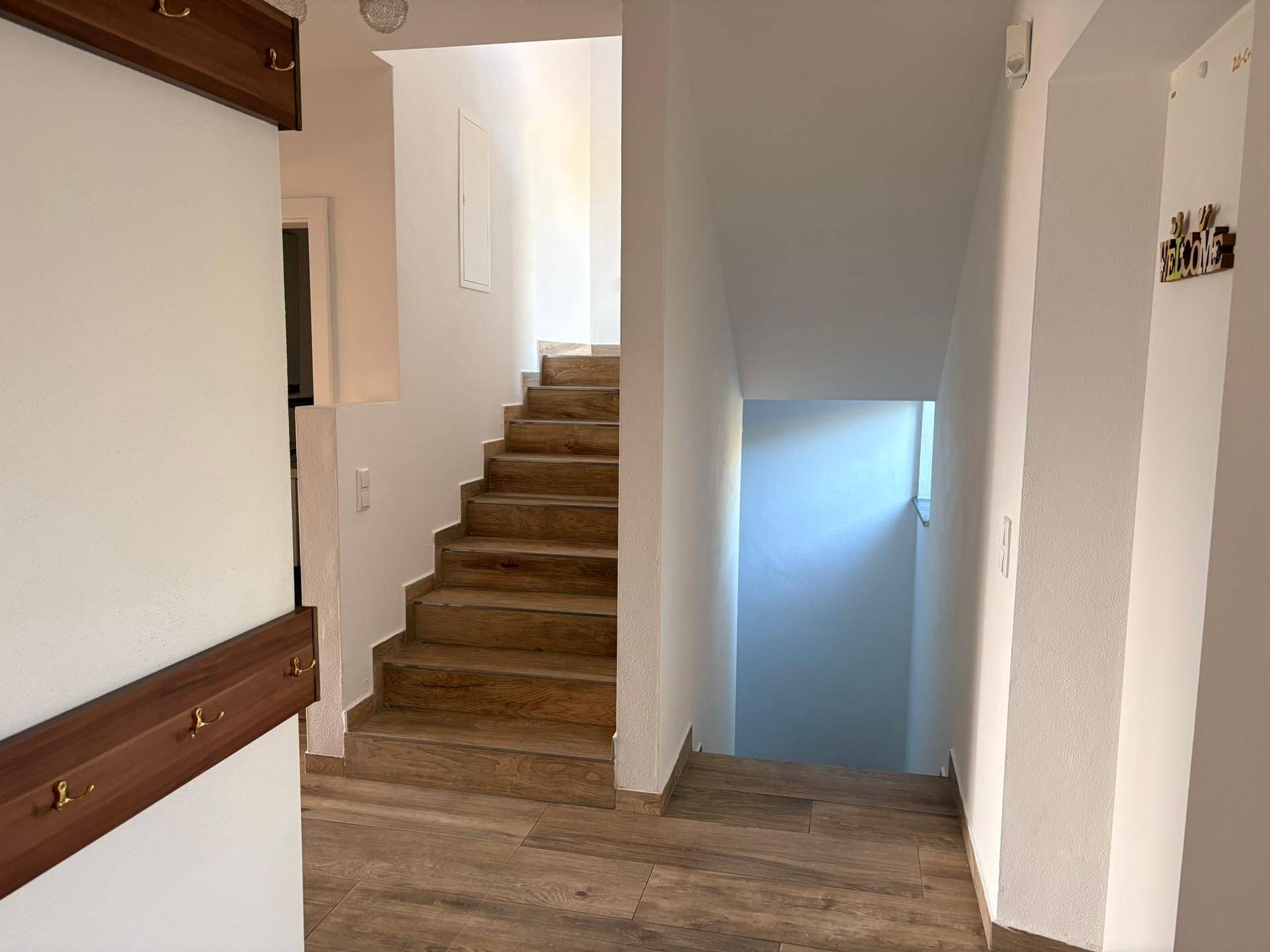 Heller Flur mit Holztreppe, die in die oberen und unteren Etagen führt.