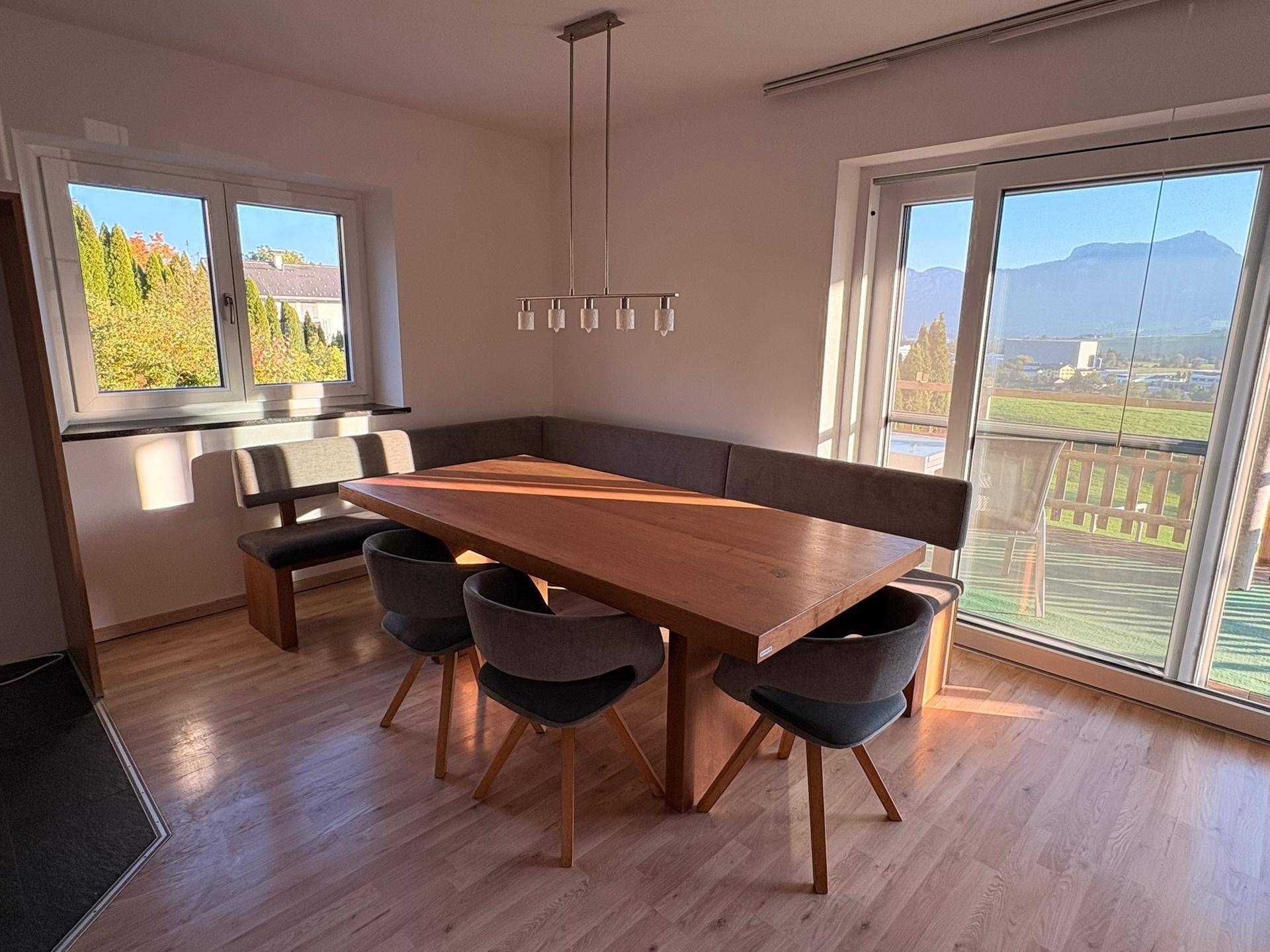 Gemütlicher Essbereich mit großem Holztisch, Eckbank und weitem Blick auf die Berge.