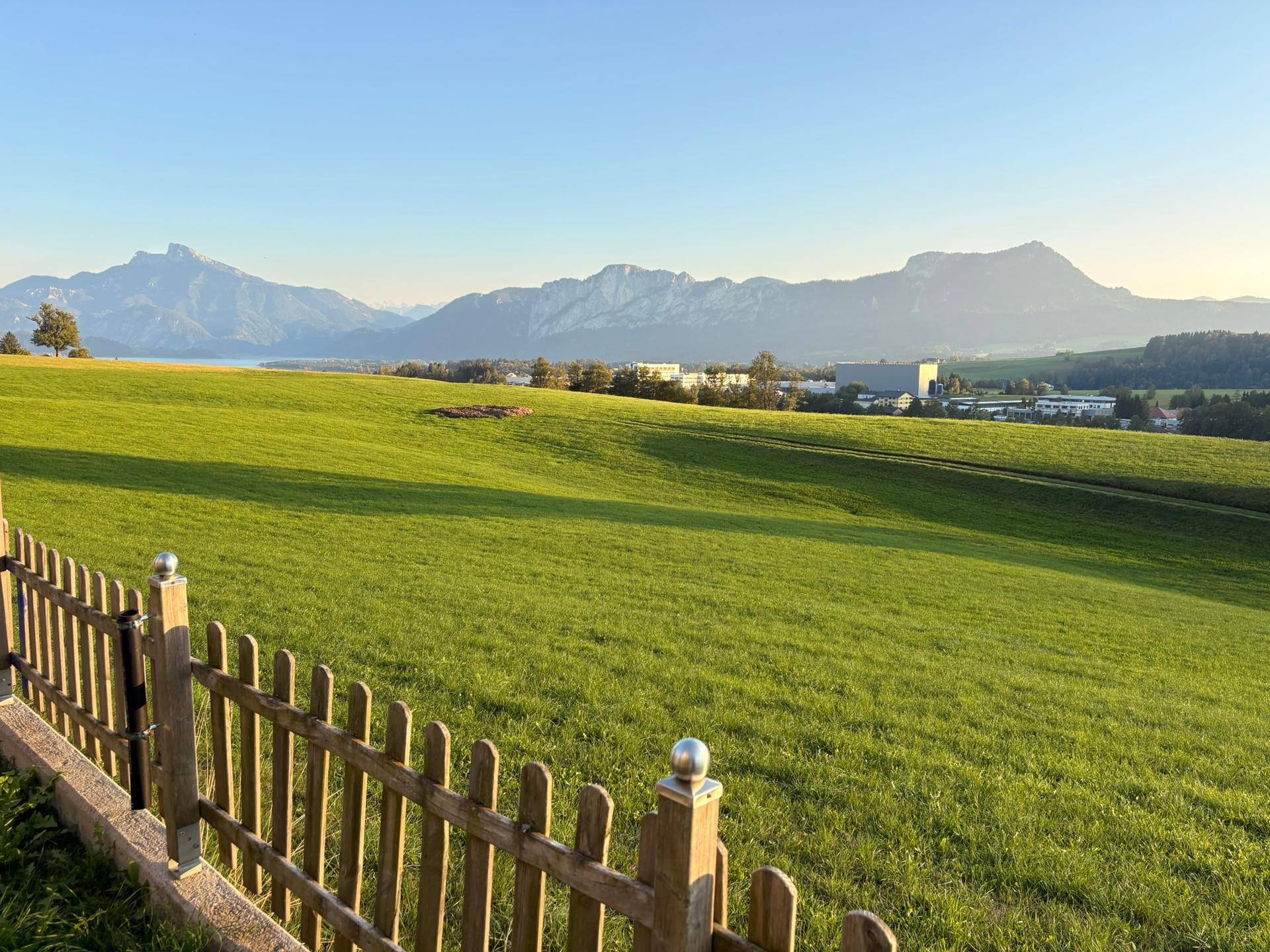 Weitläufiger Panoramablick über grüne Felder und majestätische Berge in der Ferne.
