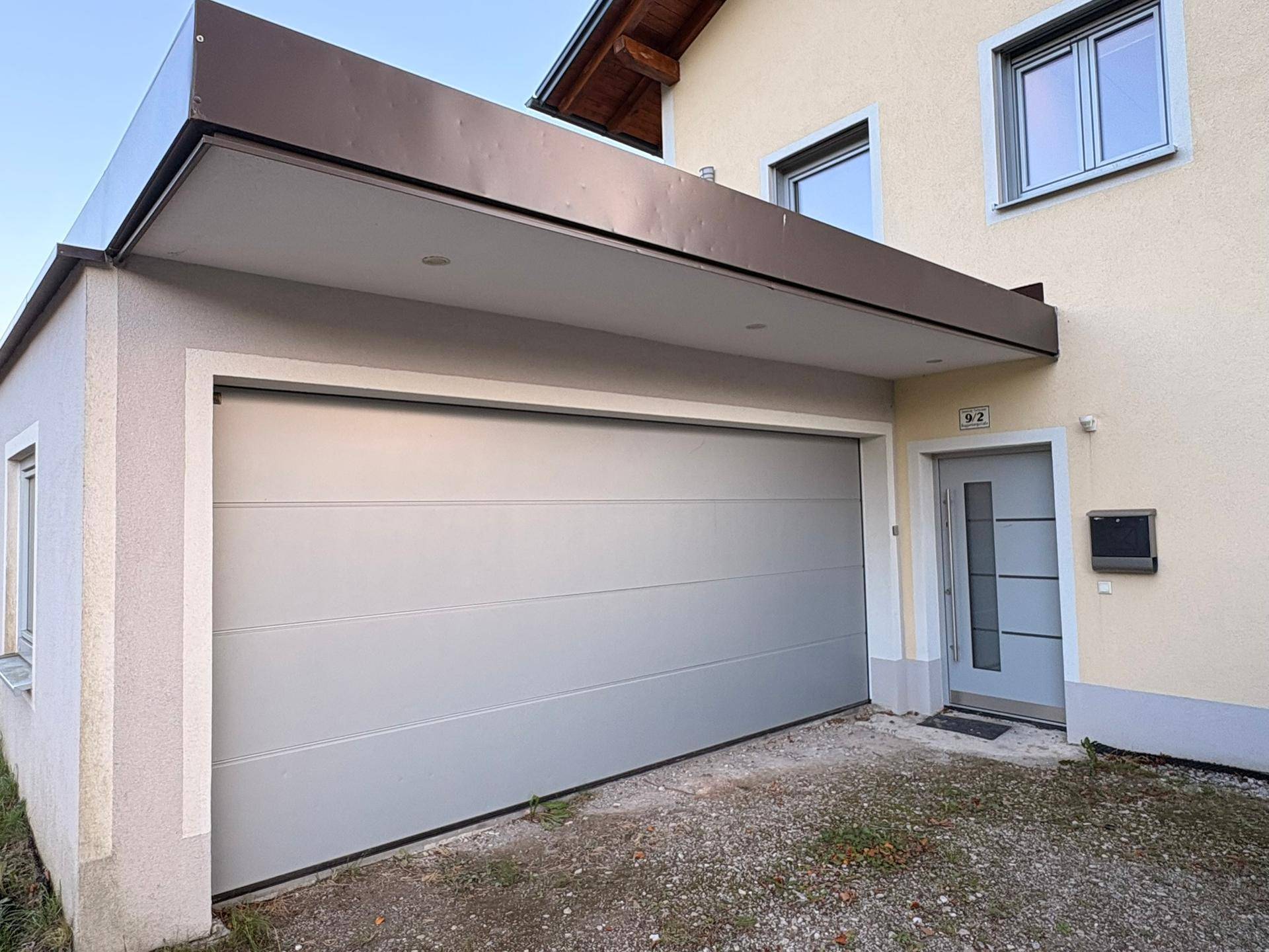 Eingangsbereich des Hauses mit moderner Haustür und integrierter Garage.
