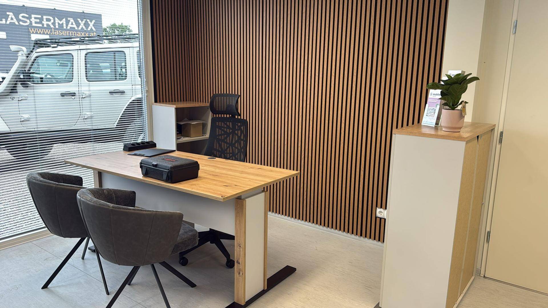 Modernes Büro mit Holzwandverkleidung, Schreibtisch und großem Fenster mit Blick nach draußen.