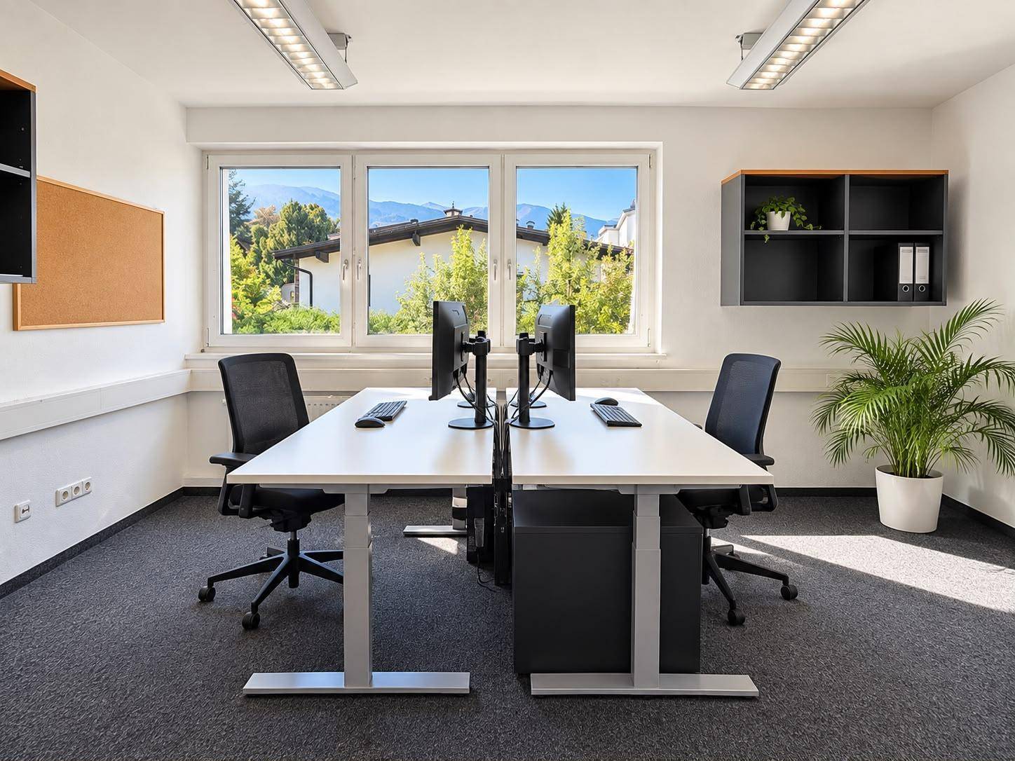 Geräumiges Büro mit zwei Arbeitsplätzen, Computern und einem großen Fenster mit Bergblick.