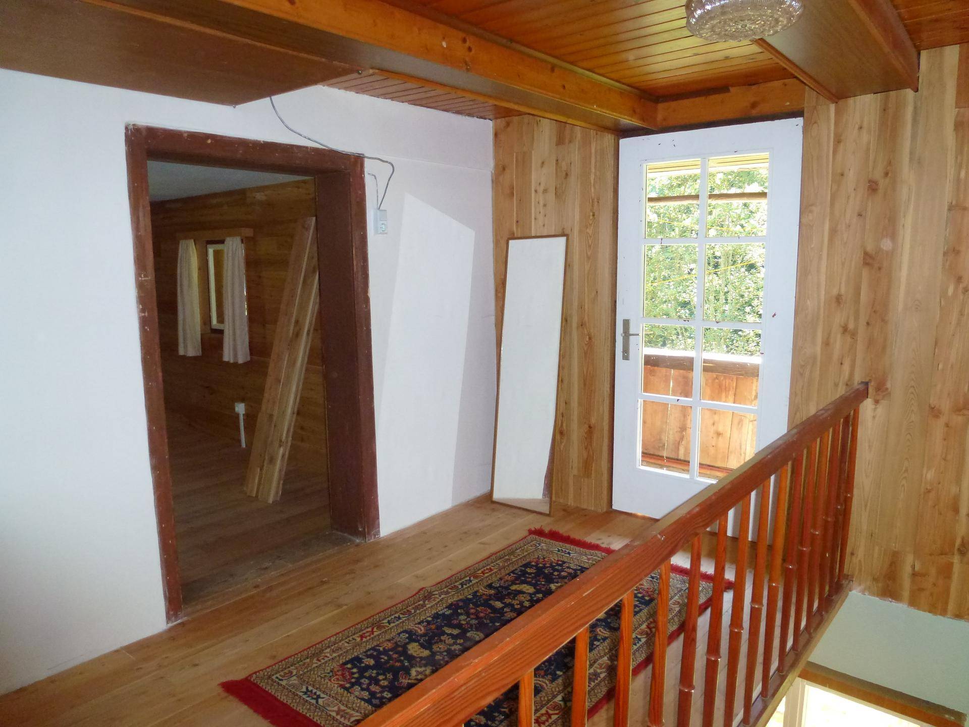 Heller Flur mit Holzboden, Holzverkleidung und einer Tür, die zu einem Balkon führt.