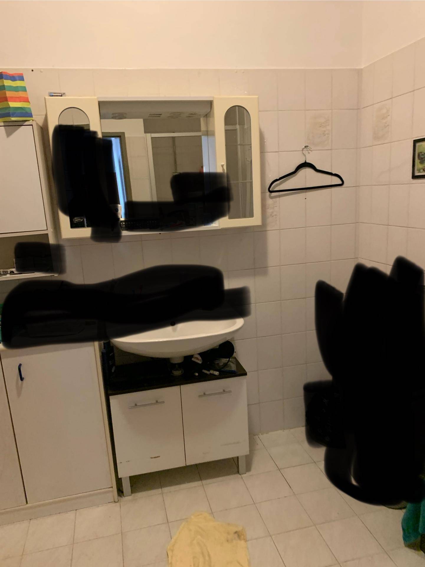 Badezimmer mit Waschbecken, Spiegelschrank und weißen Fliesen an den Wänden.