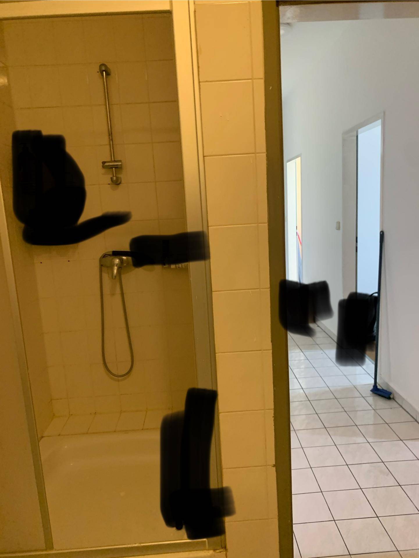 Badezimmer mit Duschwanne und weißen Fliesen, die einen Blick in den Flur ermöglichen.