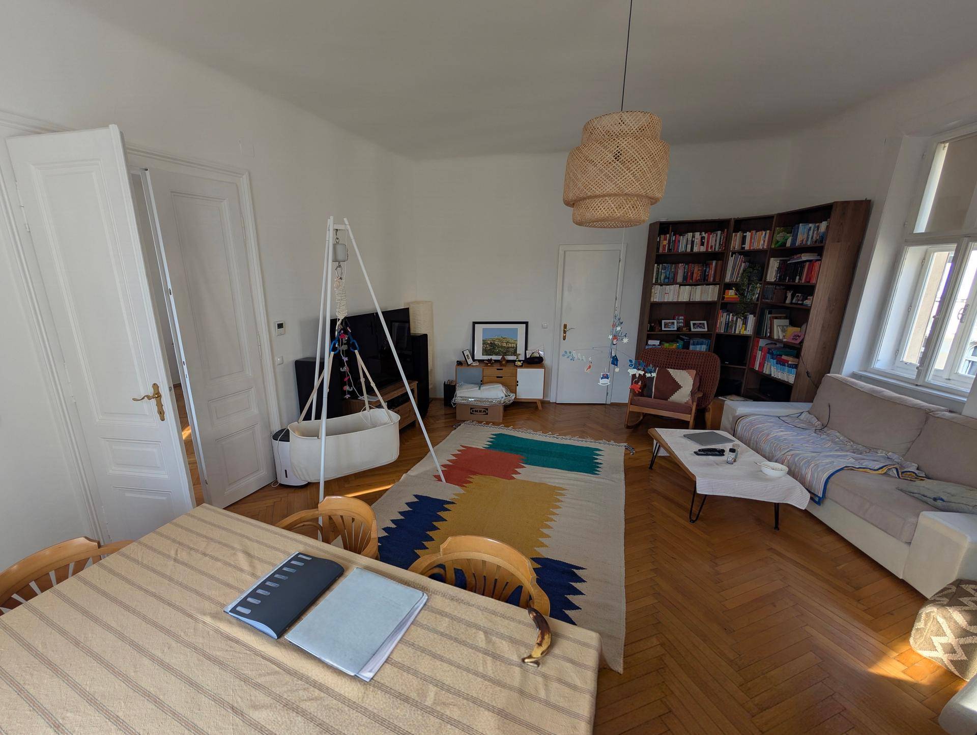 Geräumiger Wohn- und Essbereich mit Bücherregal, Parkettboden und viel Tageslicht.