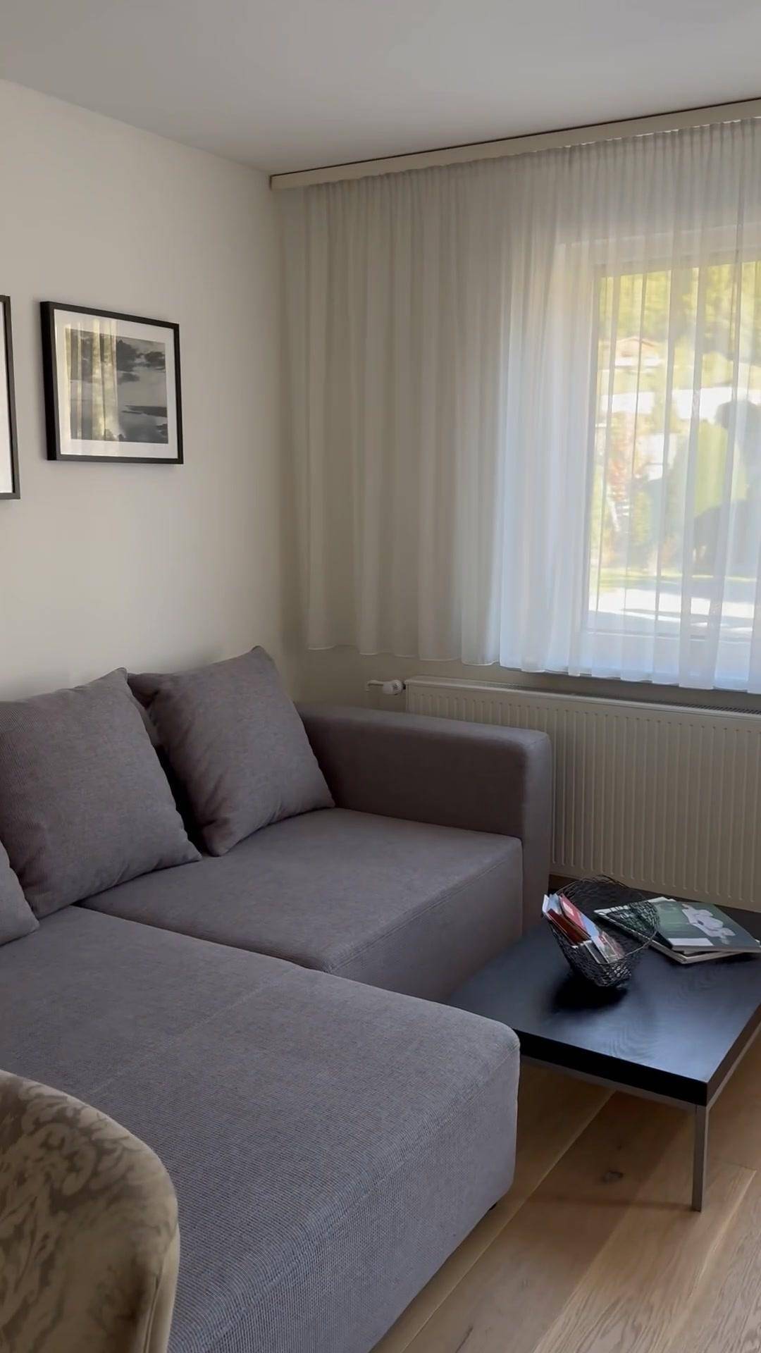 Gemütliches Wohnzimmer mit grauem Ecksofa, Couchtisch und hellem Holzboden.