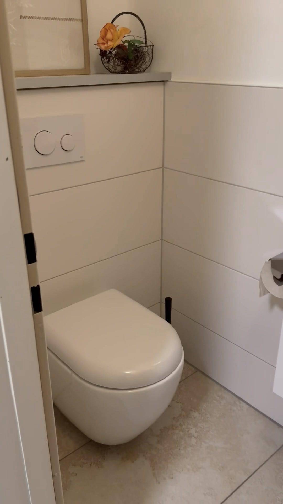 Gäste-WC mit wandmontierter Toilette und modernen, hellen Fliesen.