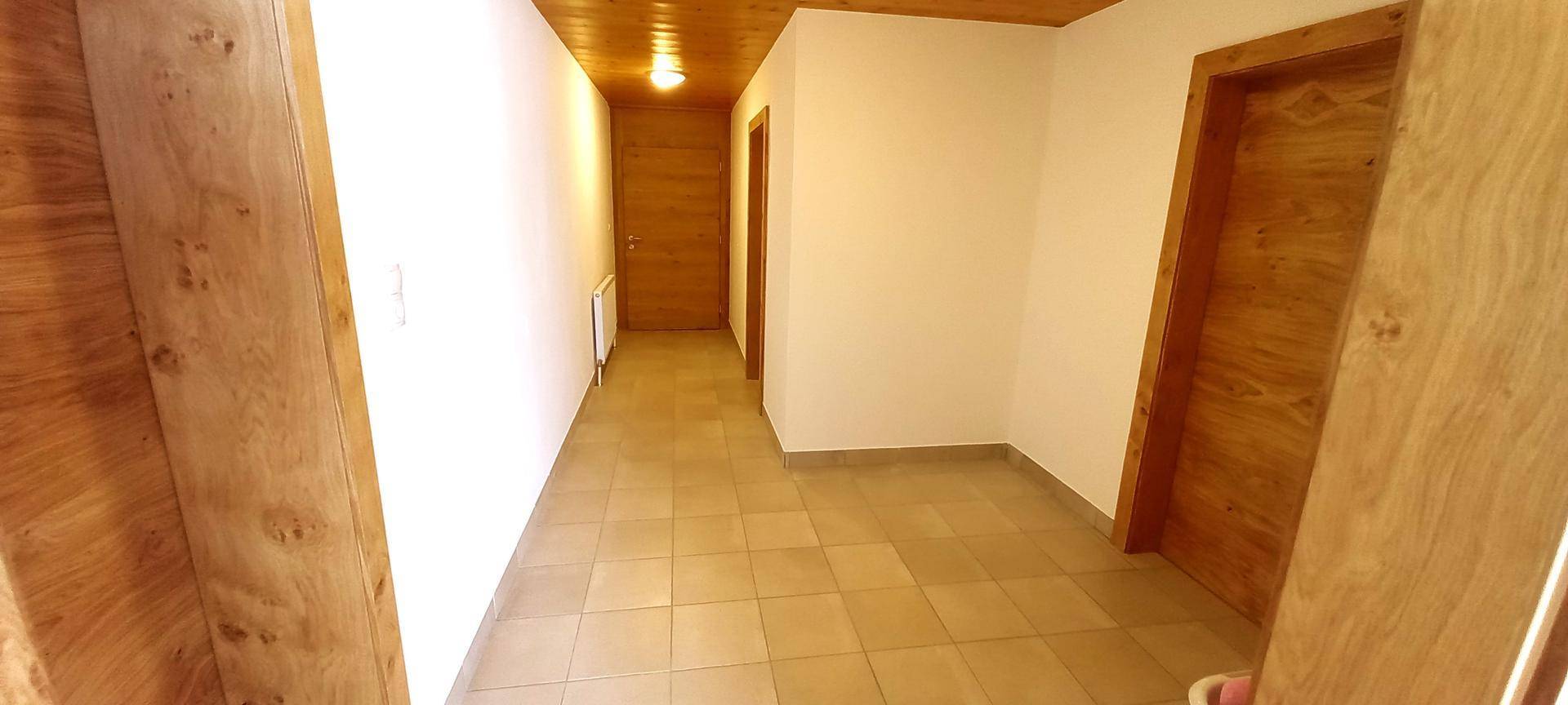 Heller Flur mit Fliesenboden, Holztüren und einer Holzdecke, die Wärme ausstrahlt.
