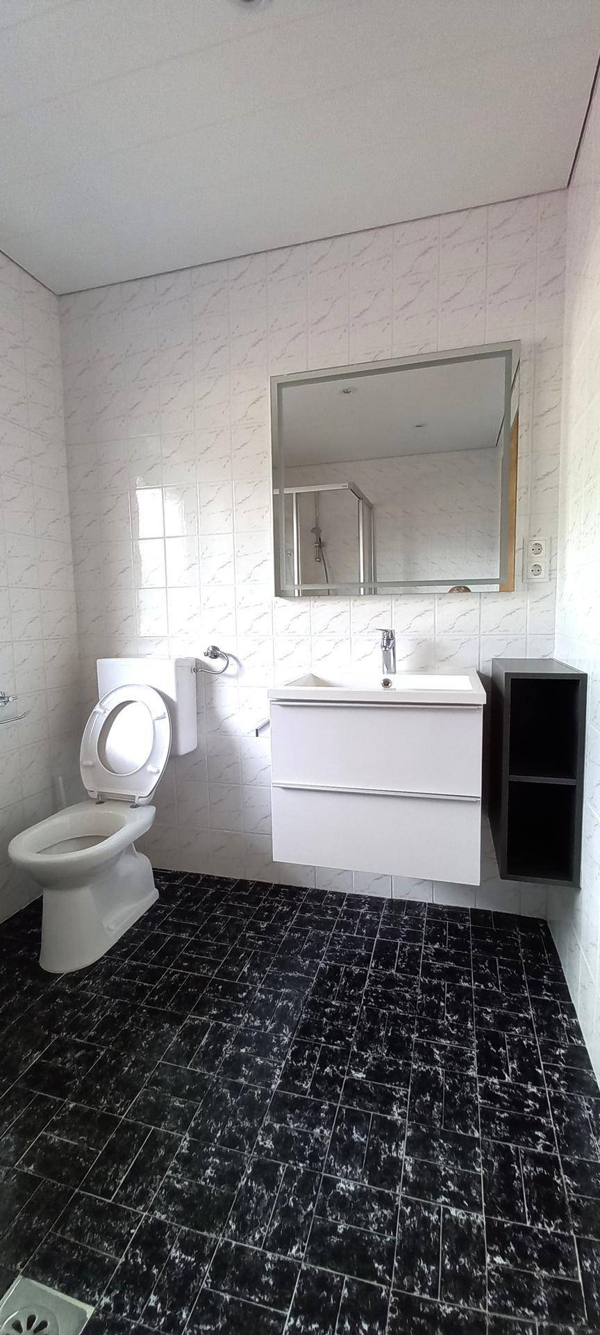 Modernes Badezimmer mit schwarzen Fliesen, weiß gefliesten Wänden und einem Waschbecken mit Spiegelschrank.