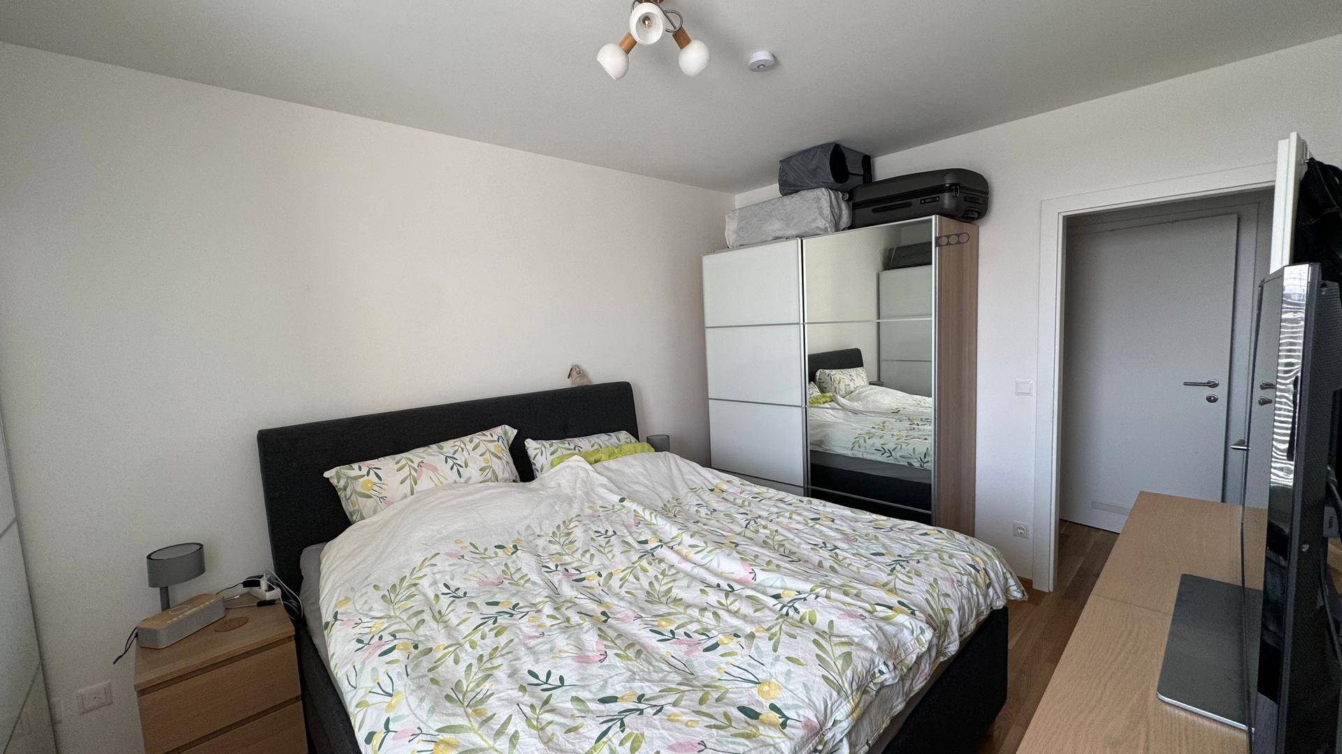 Schlafzimmer mit Doppelbett, Spiegelschrank und Holzboden.
