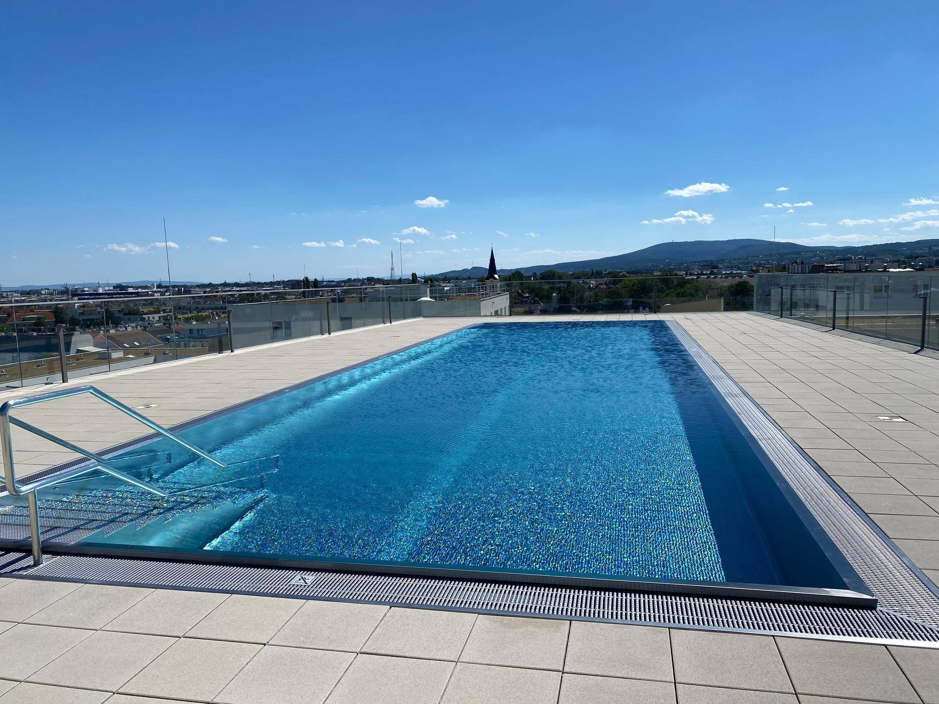 Dachterrassen-Pool mit weitem Blick über die Stadt und die umliegenden Berge.