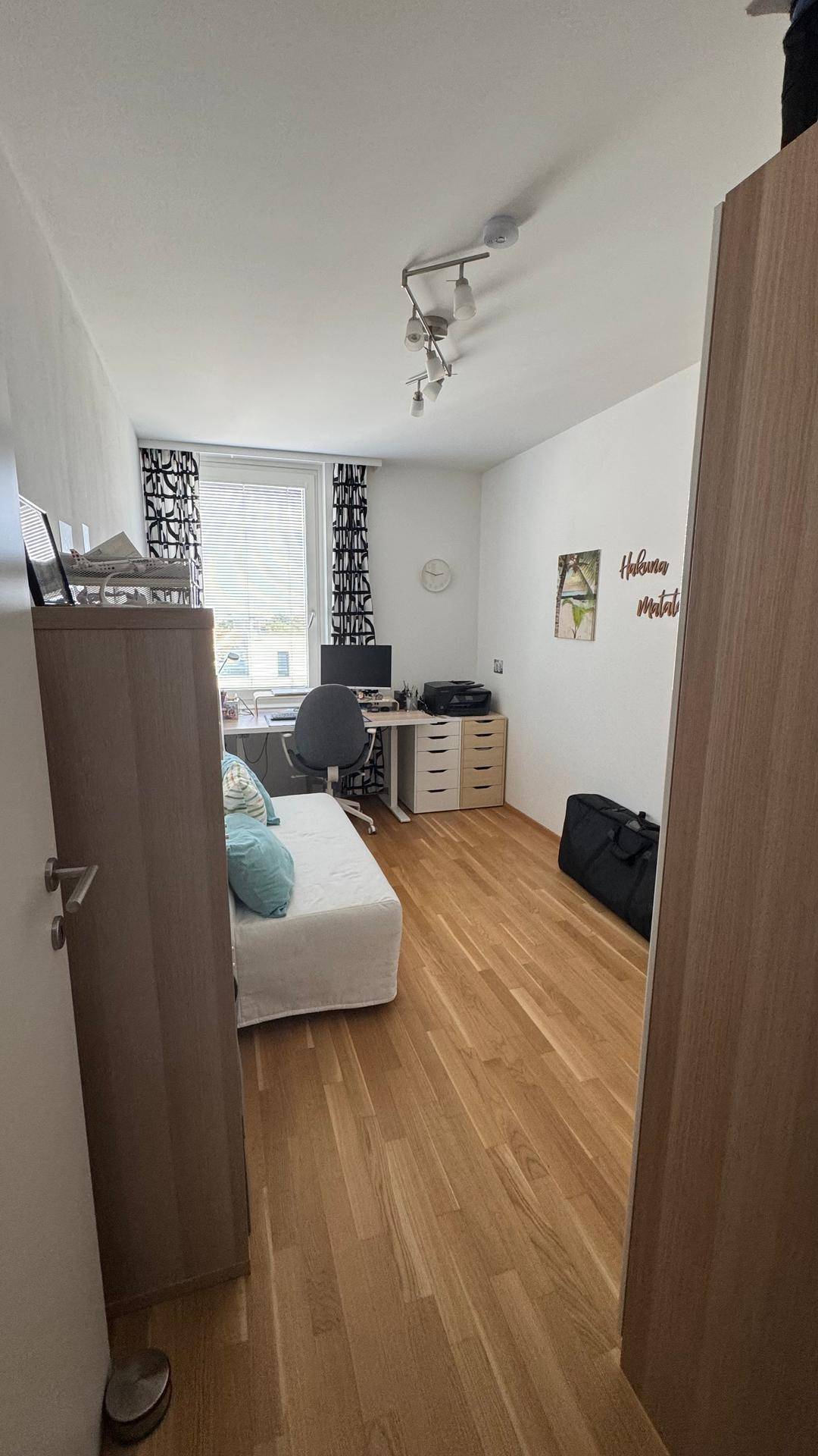 Helles Arbeitszimmer mit Schreibtisch, Stuhl und Holzboden.
