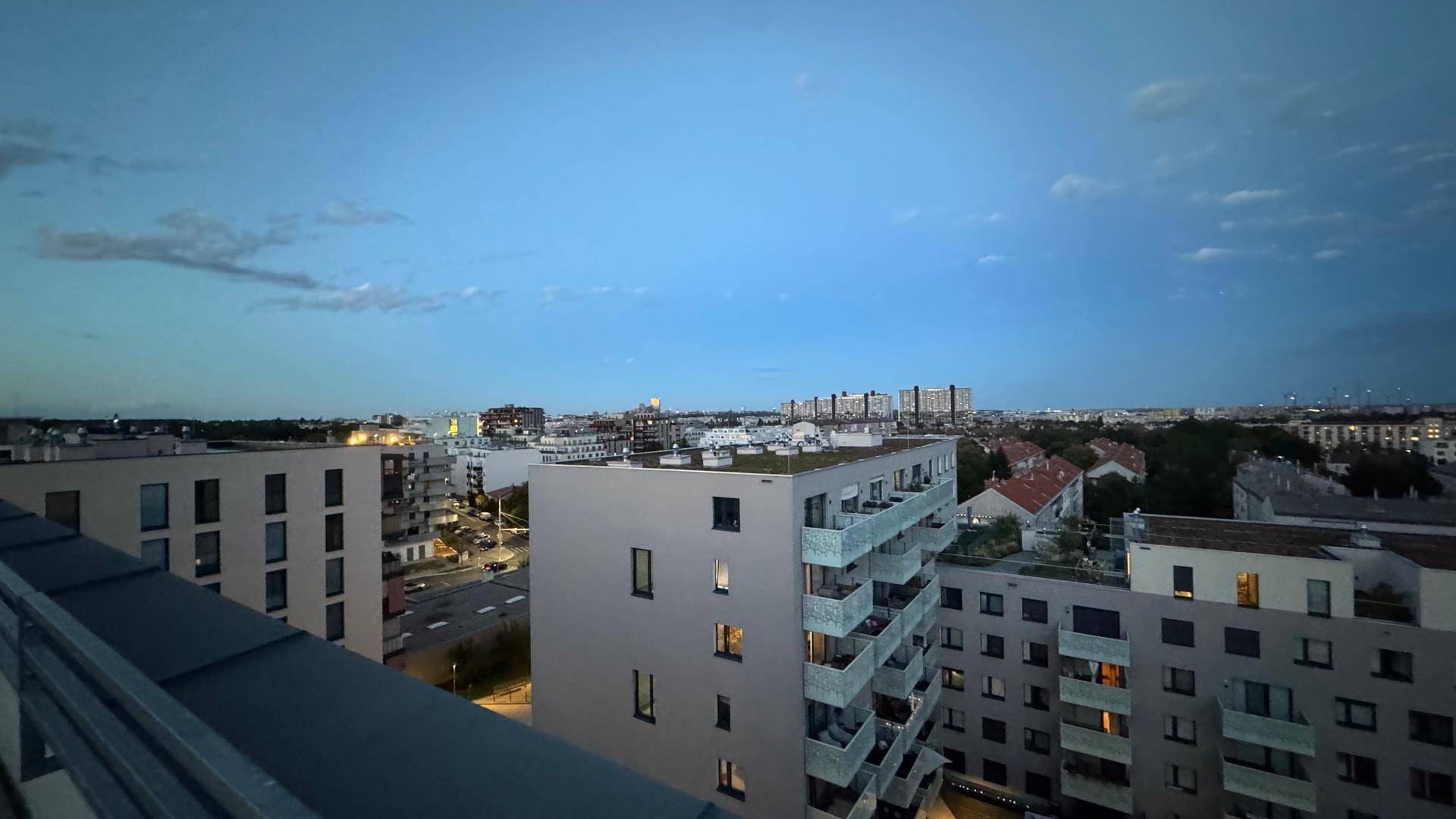 Panoramablick über die Stadt bei Dämmerung von einer Dachterrasse.