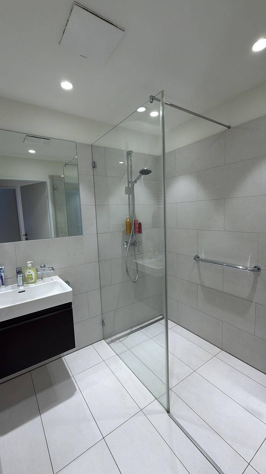 Helles Badezimmer mit begehbarer Dusche, modernem Waschbecken und praktischem Haltegriff.