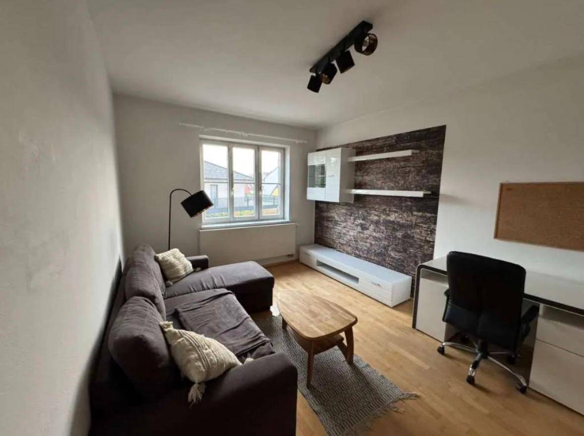 Helles Wohnzimmer mit Sofa, Couchtisch und Schreibtisch, bietet eine angenehme Wohnatmosphäre.