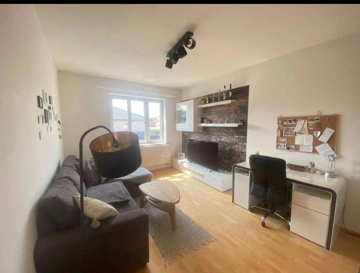 Helles Wohnzimmer mit großem Fenster, Sofa, Schreibtisch und Medieneinheit, bietet viel Tageslicht.