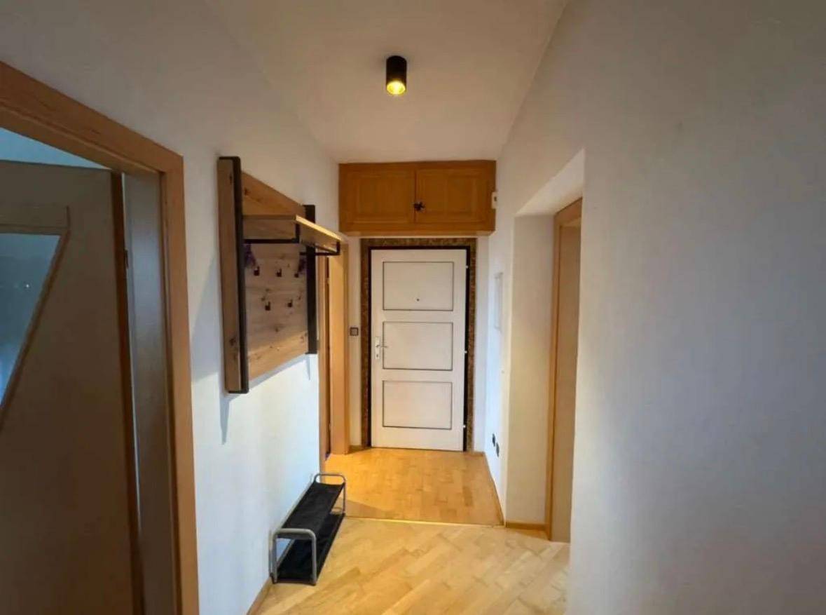 Eingangsbereich mit Holzboden, Garderobe und Schuhregal, führt zur Wohnungstür.